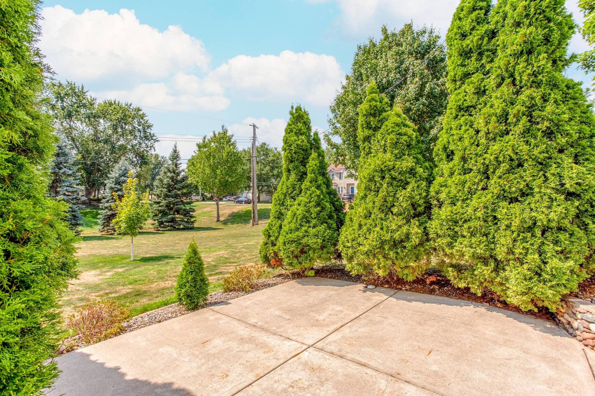 A closer look at the patio showcases its privacy, established landscaping, and towering Arborvitae treesa welcoming spot to unwind and enjoy the park-like surroundings.