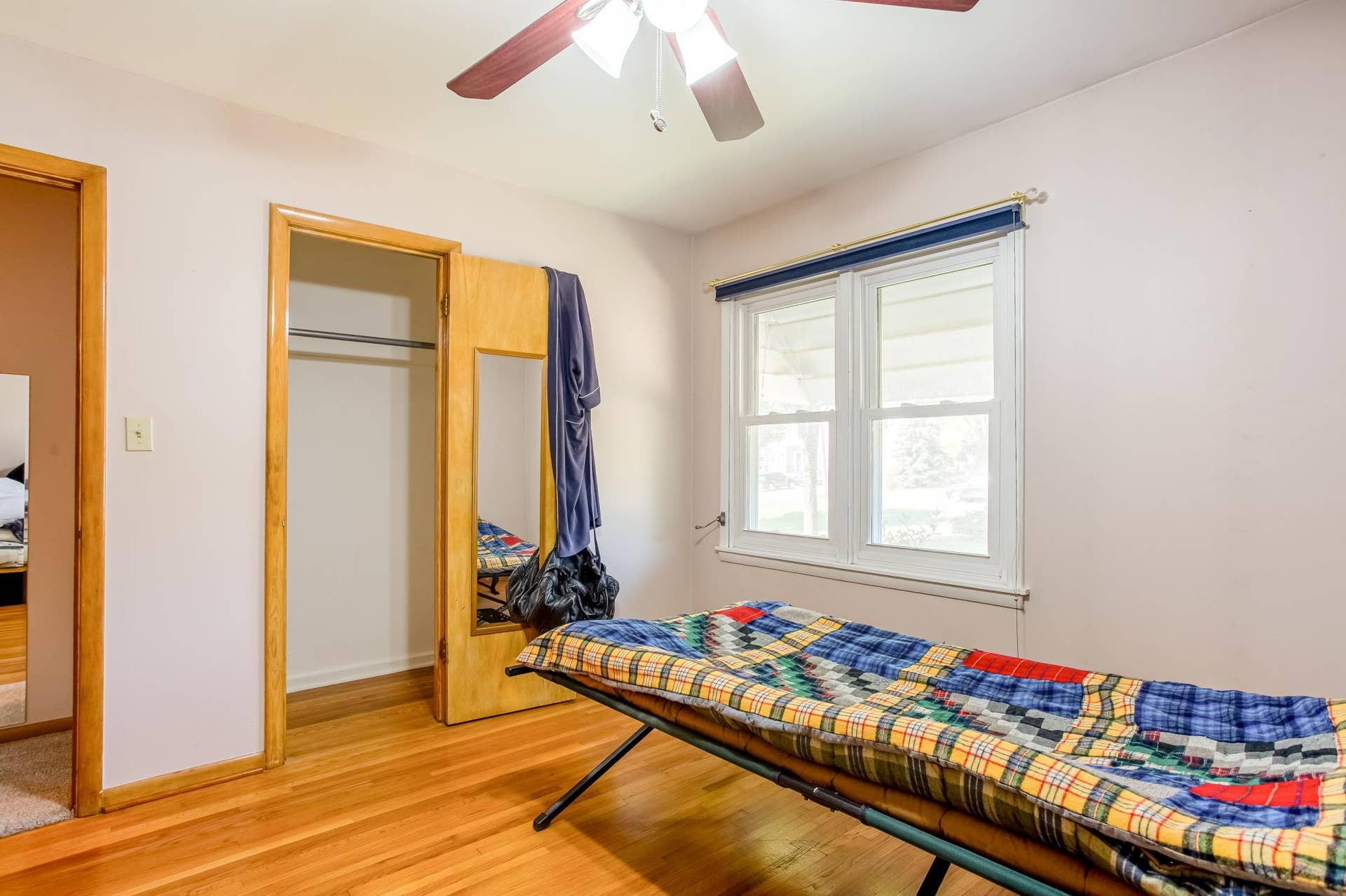 Additional view highlights the bedroom's hardwood floors, natural light, and convenient closet space.
