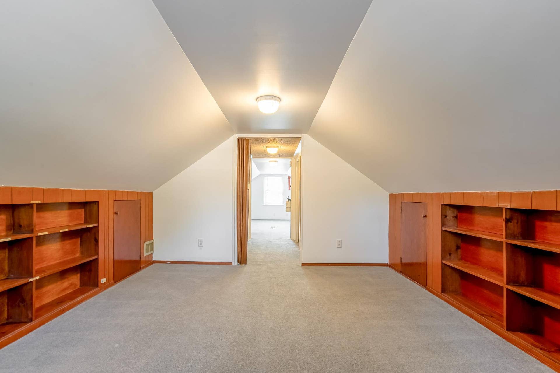 Additional view showcases the upper-level room's spacious footprint, built-in shelving, and practical storage areas.
