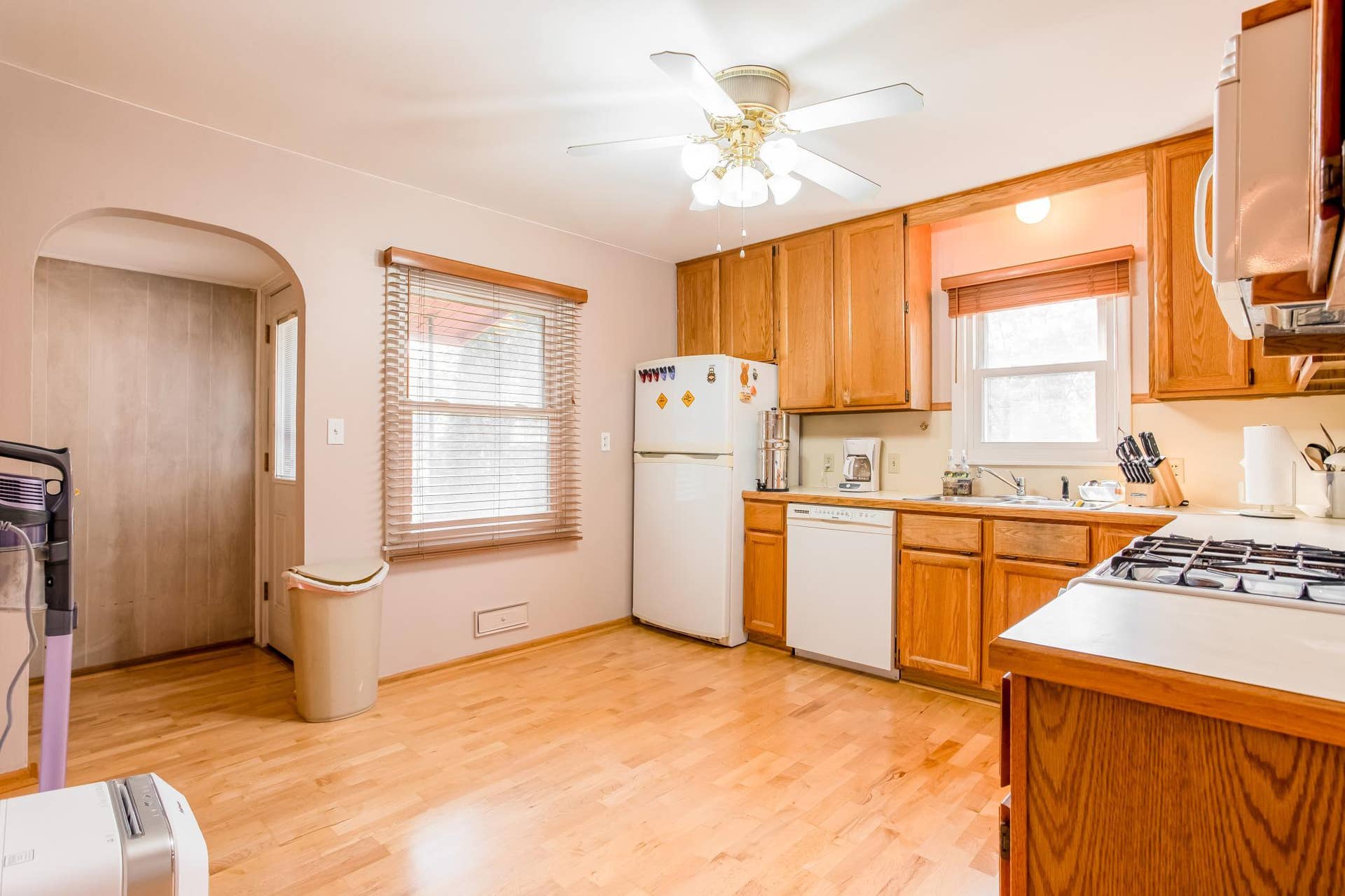 Bright kitchen featuring hardwood birch flooring, abundant cabinetry, generous workspace, and convenient access to the backyard.
