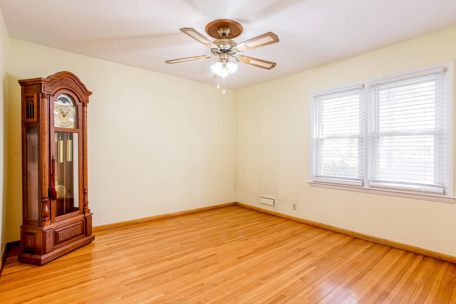 Main-level bedroom features beautiful hardwood floors, a ceiling fan, and multiple windows providing abundant natural light.