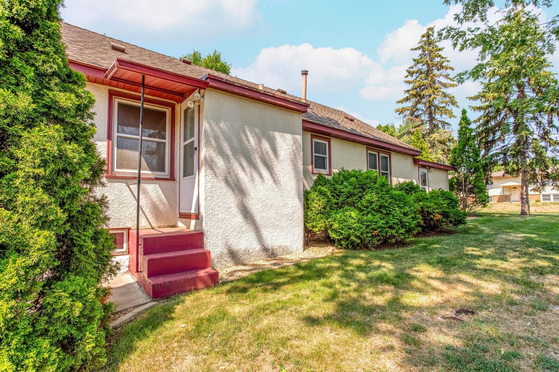 Convenient rear entrance provides easy access to the home while mature landscaping adds shade, greenery, and privacy.