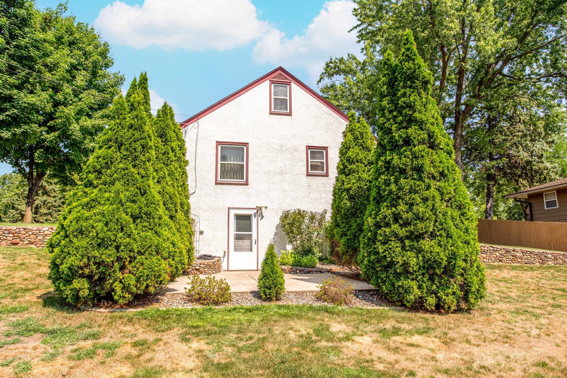 The home's private patio is tucked between mature Arborvitae trees, creating a peaceful and secluded space for relaxing or entertaining outdoors.