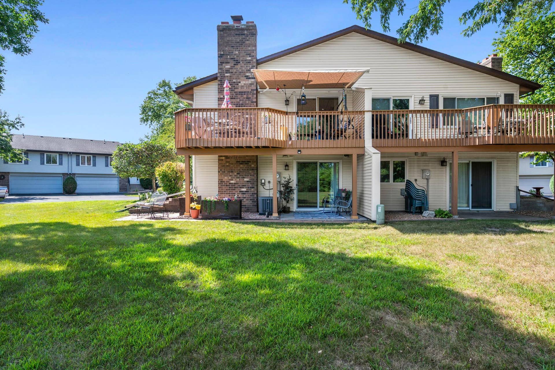 14333 91st Place N, Maple Grove, MN 55369 Home is on the left. View showcases the yard, big deck and covered patio.
