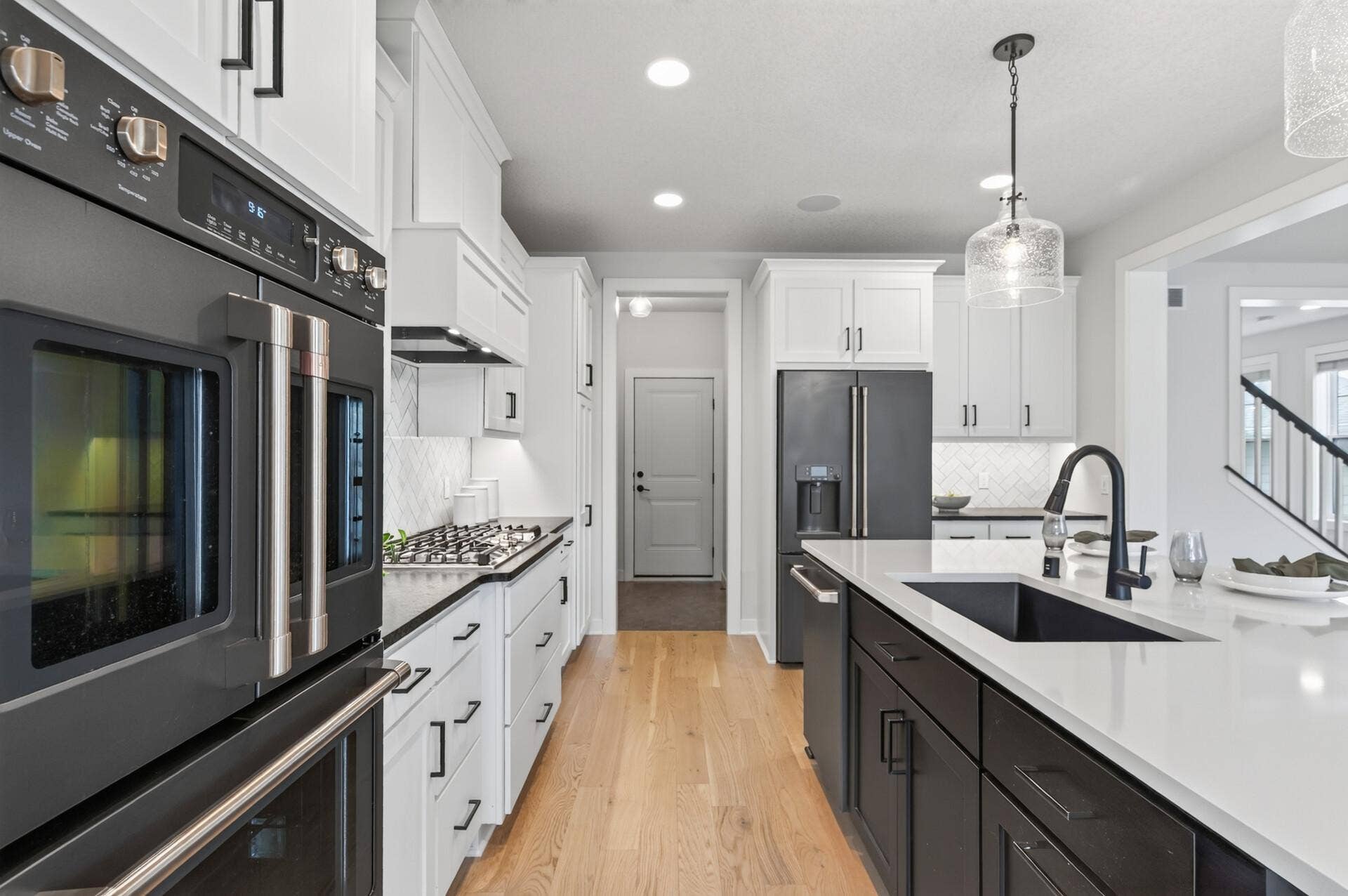 9960 Arrowwood Trail, Woodbury, MN 55129 High-end appliances elevate this stunning kitchen: double wall ovens, a 36" gas cooktop for precision cooking, and a sleek black French door fridge with water dispenser for everyday convenience.