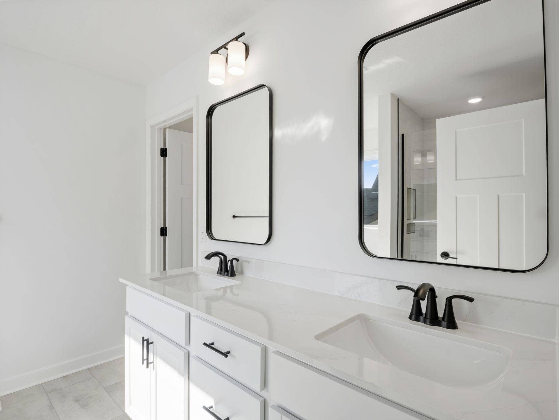 Quartz countertops, plate-glass mirrors, raised-height cabinets and Moen Glyde faucets unite at this oversized vanity