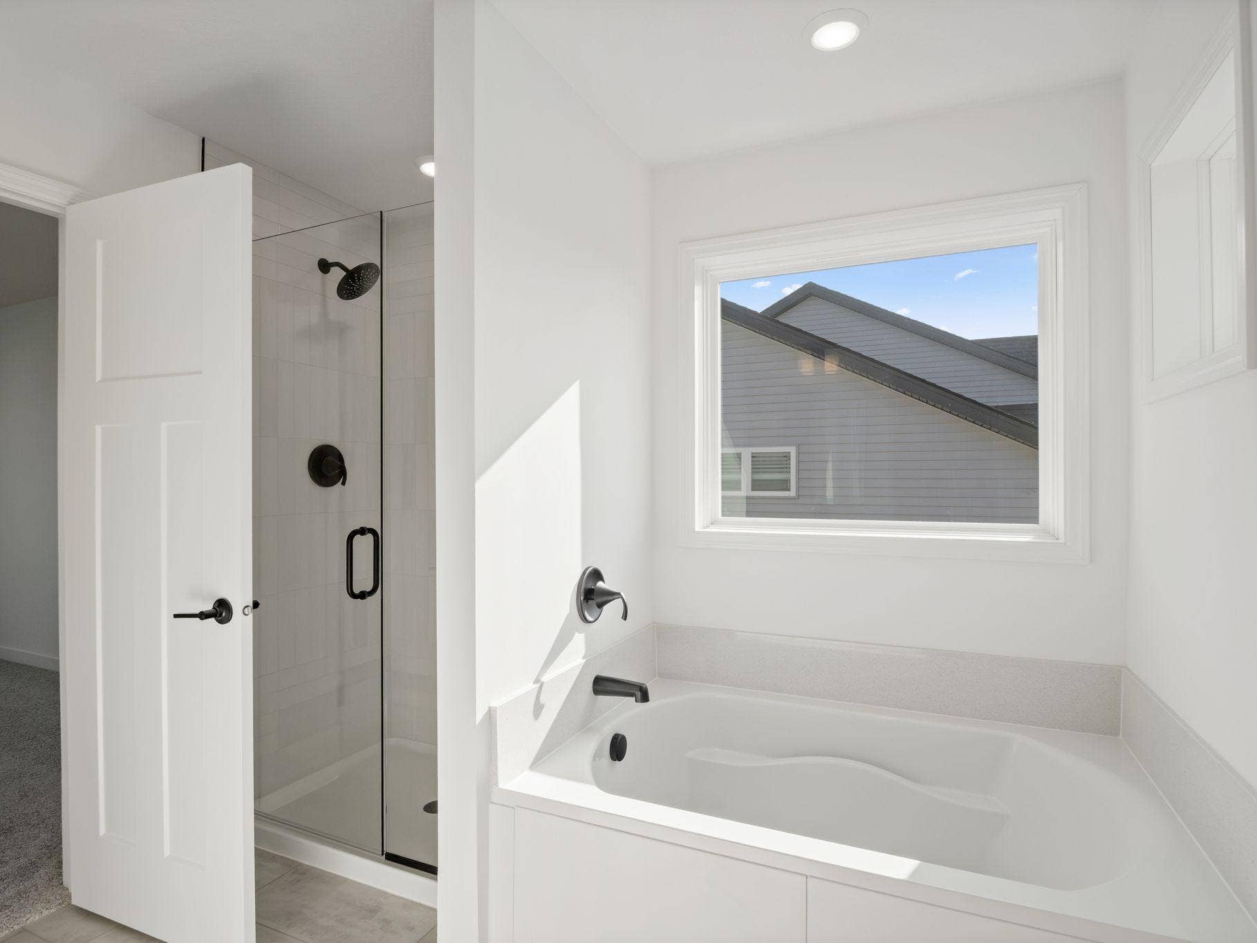 A glass-enclosed shower with Sterling Vikrell surround, built-in seating and an oversized shower head are featured in the bathroom