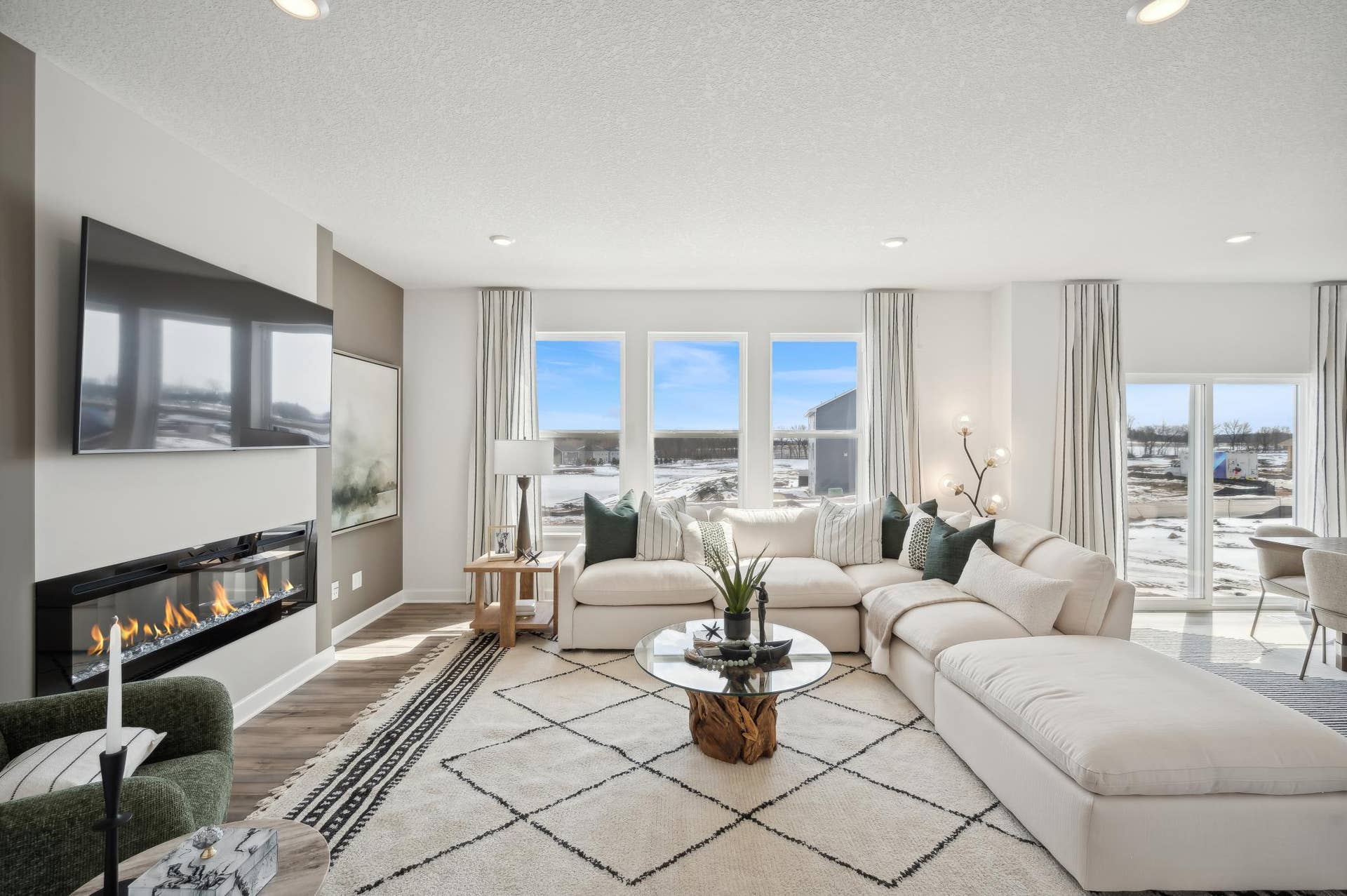 (Photo of model home, finishes will vary) The spacious family gathering area seamlessly connects to the kitchen area, perfect for entertaining. It also features many large windows providing warm natural light and a fireplace.