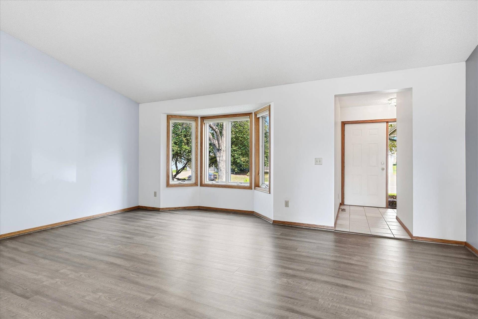 9225 Queens Gardens, Brooklyn Park, MN 55443 Bright and spacious living room featuring LVP flooring, vaulted ceilings, and a large bayed window that fills the space with natural light.
