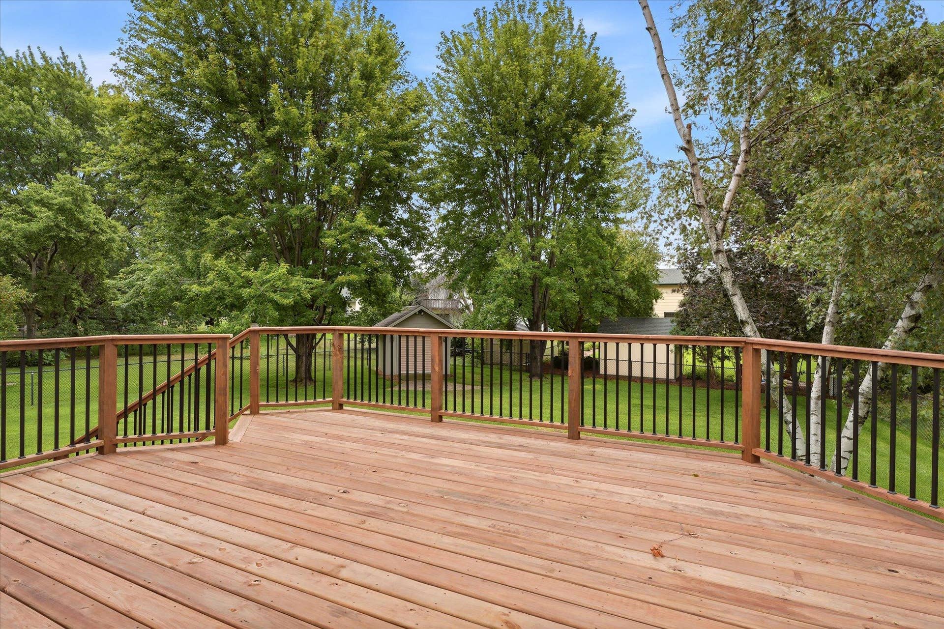 9225 Queens Gardens, Brooklyn Park, MN 55443 New cedar deck (2025) located just off the kitchen provides a convenient extension of the living space, perfect for grilling, outdoor dining, and enjoying the backyard.