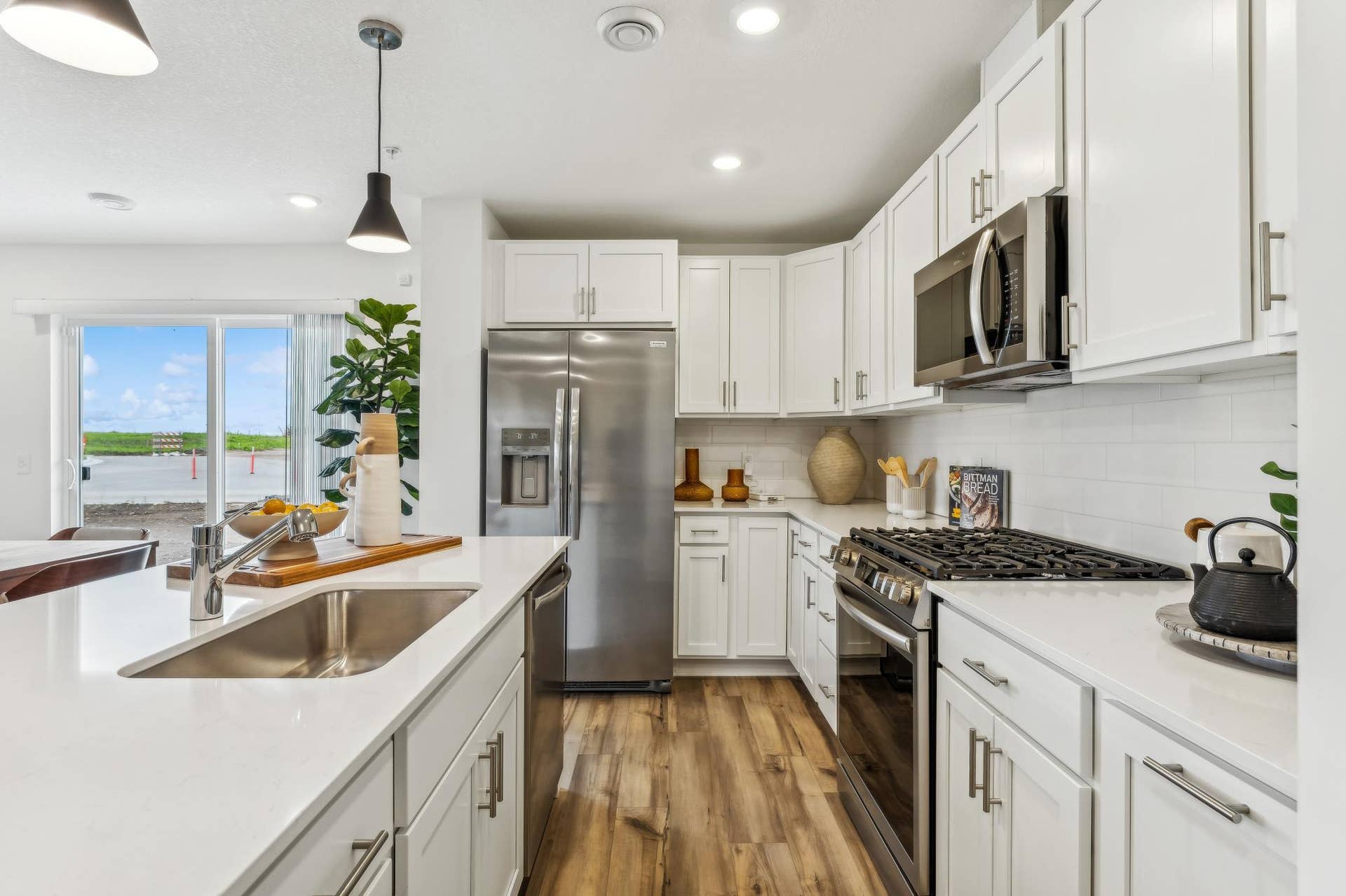 5431 Long Pointe Pass, Woodbury, MN 55129 (Photo of a model home, actual homes finishes will vary) The beautiful kitchen has sleek white cabinets, SS finish appliances, luxury vinyl planking, tons of lighting and natural light as well as an island.