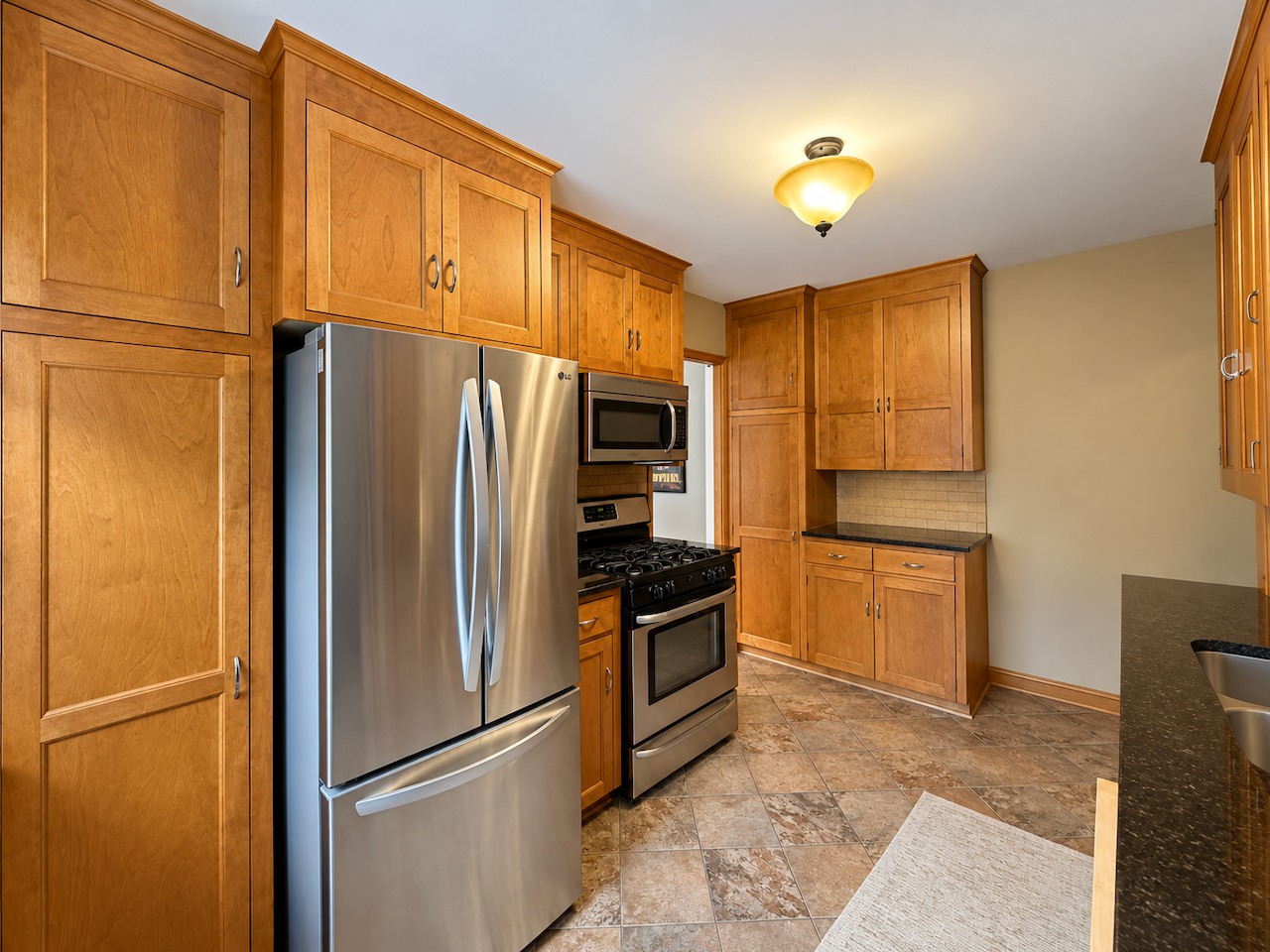 5921 Chicago Avenue S, 17, Minneapolis, MN 55417 Tall wood cabinets provide substantial storage for groceries and cookware, with more cabinets and counter space across the kitchen. A gas range and stainless steel appliances complete the setup.