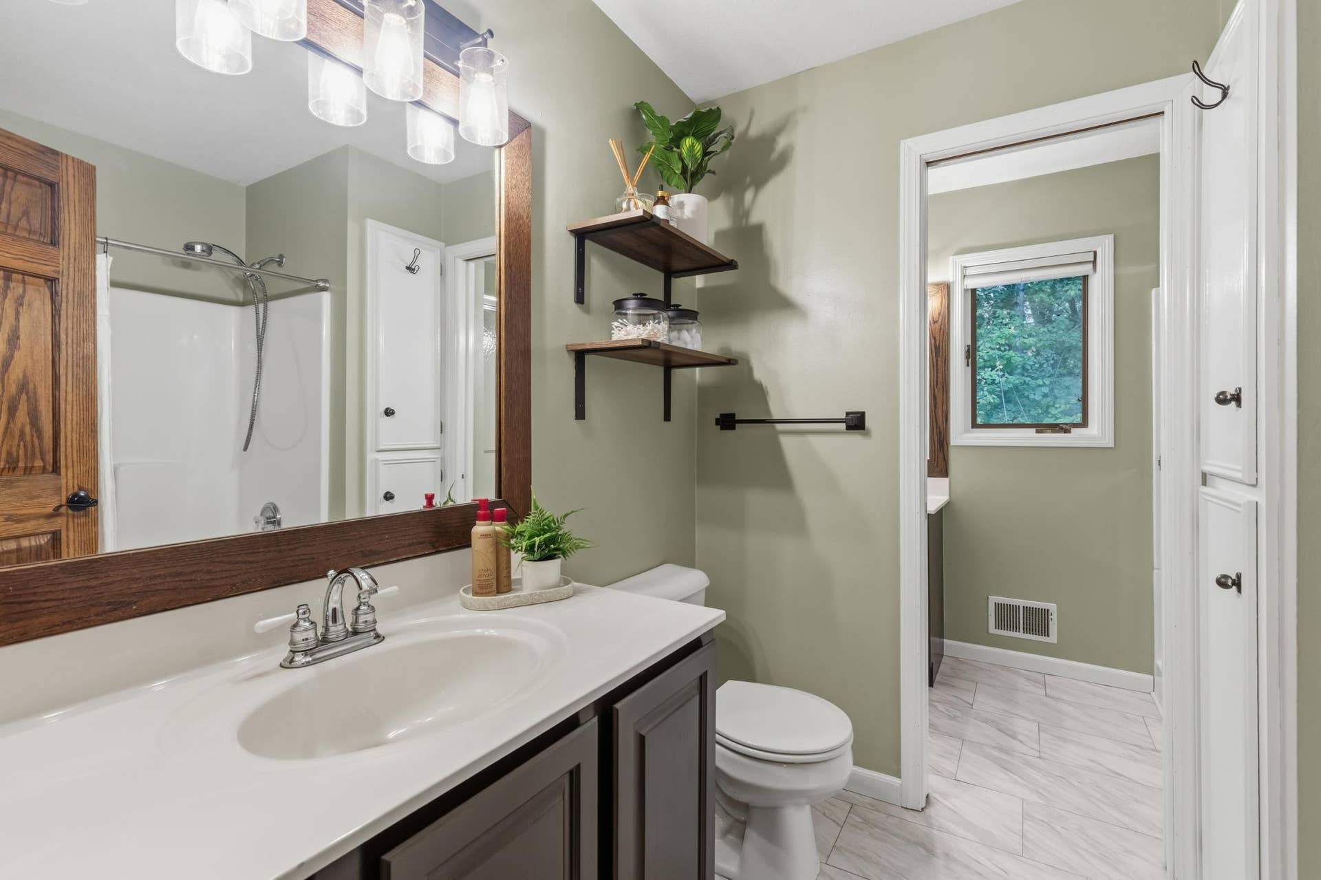 15469 Fish Point Road SE, Prior Lake, MN 55372 Full Walk-Through Bathroom offers a main bath that features a tub, linen closet, enameled vanity cabinet and laminate tile floors.