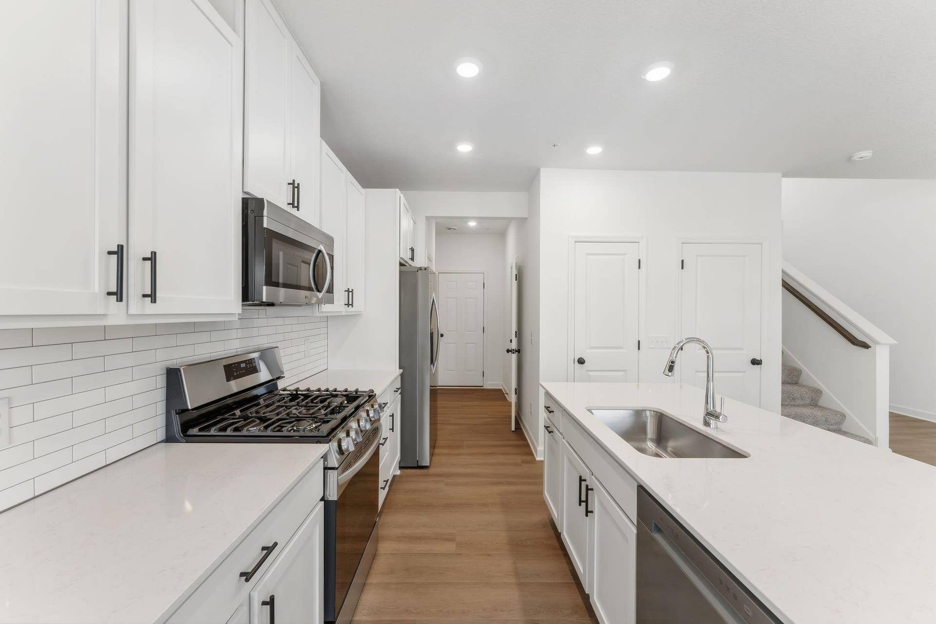 A subway tile backsplash atop the 5-burner gas cooktop with an overhead microwave meets style with functionality