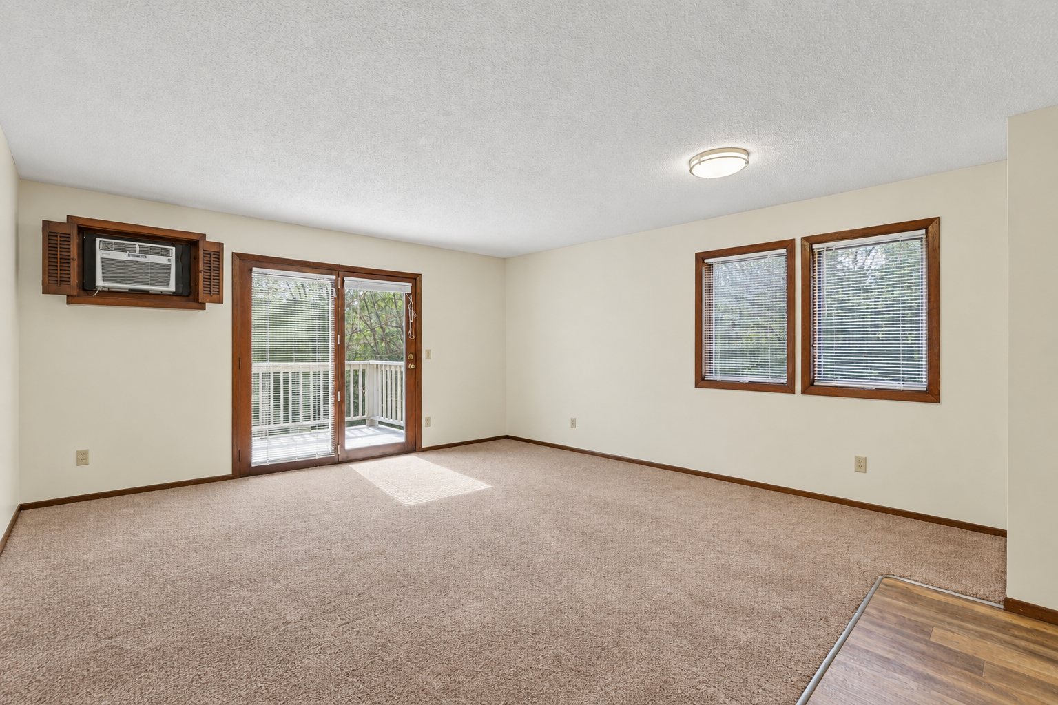 Unstaged large living room.  Entrance to deck.