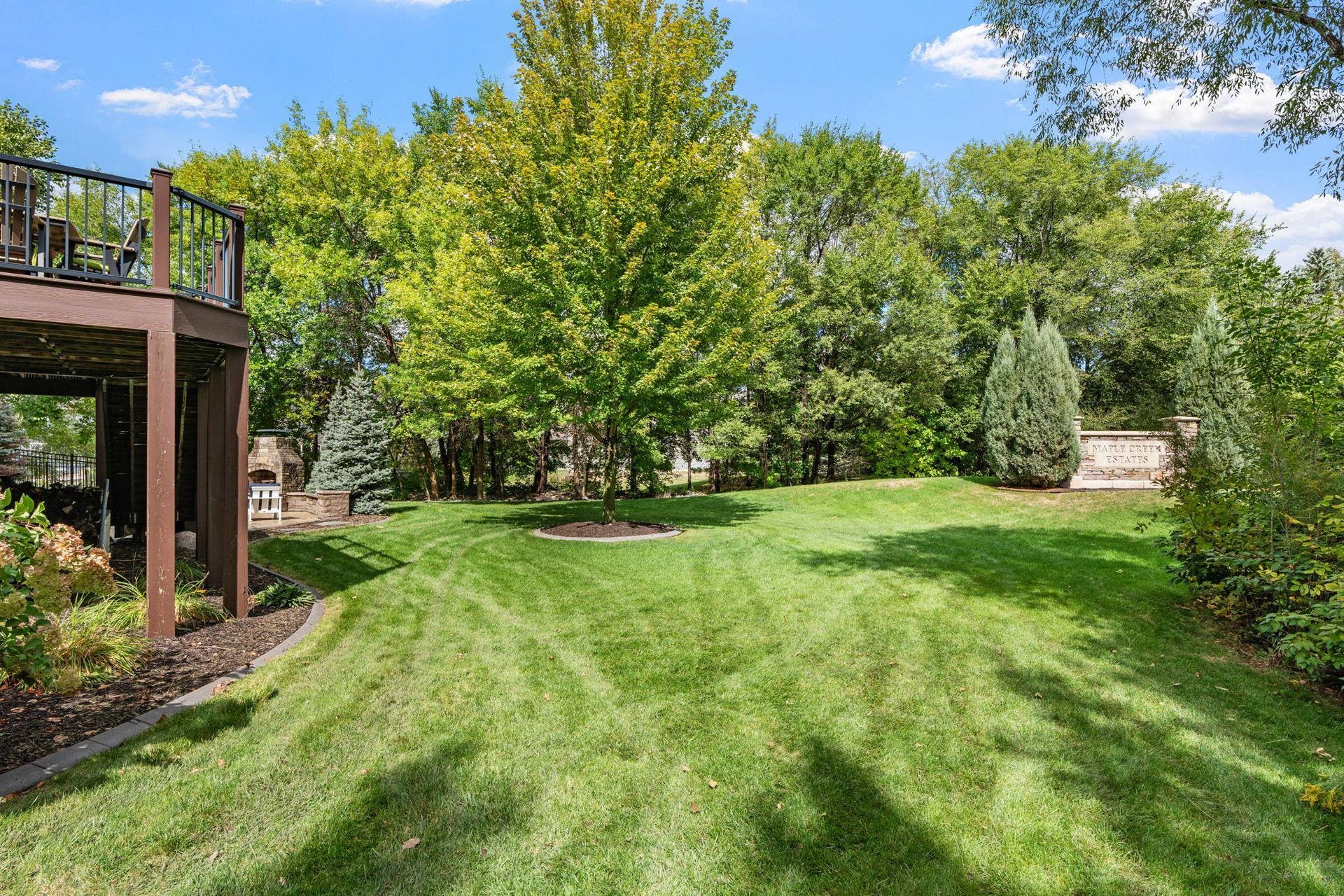 17550 73rd Avenue N, Maple Grove, MN 55311 The expansive, level lawn is framed by lush greenery and mature trees, creating a beautiful backyard setting.