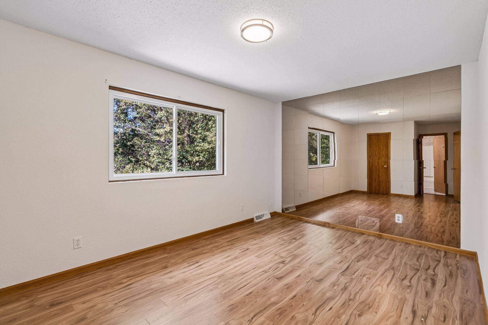 2841 Riviera Drive N, White Bear Lake, MN 55110 Upper-level primary bedroom with hardwood flooring and a mirrored accent wall.
