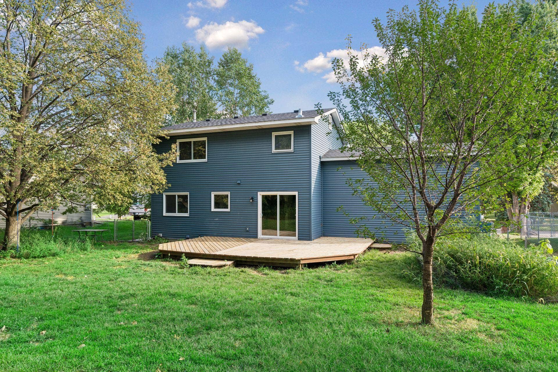 2841 Riviera Drive N, White Bear Lake, MN 55110 Backyard view of the home, deck, and surrounding greenery.