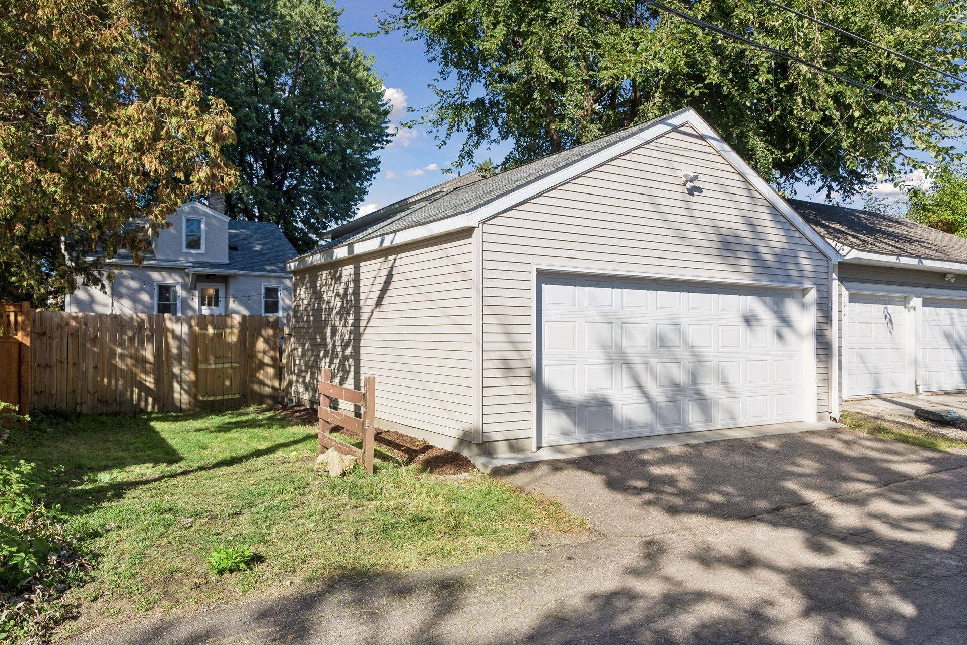 New detached two-car garage built in 2024 with EV charging outlet and extra attic storage, plus space next to the garage with potential for additional parking or a future storage shed.
