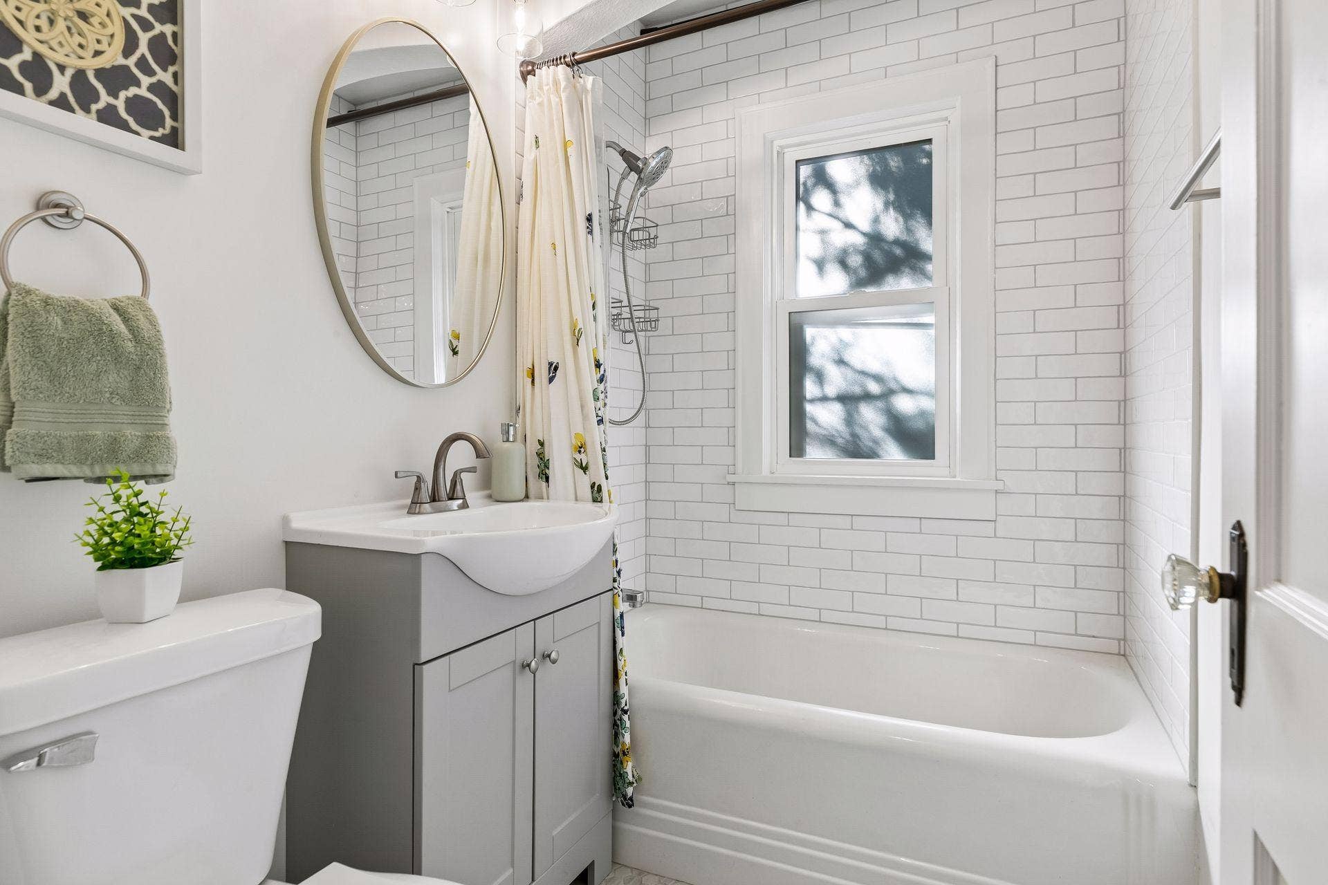 Updated full bathroom featuring a tiled tub/shower surround, modern vanity and natural light.