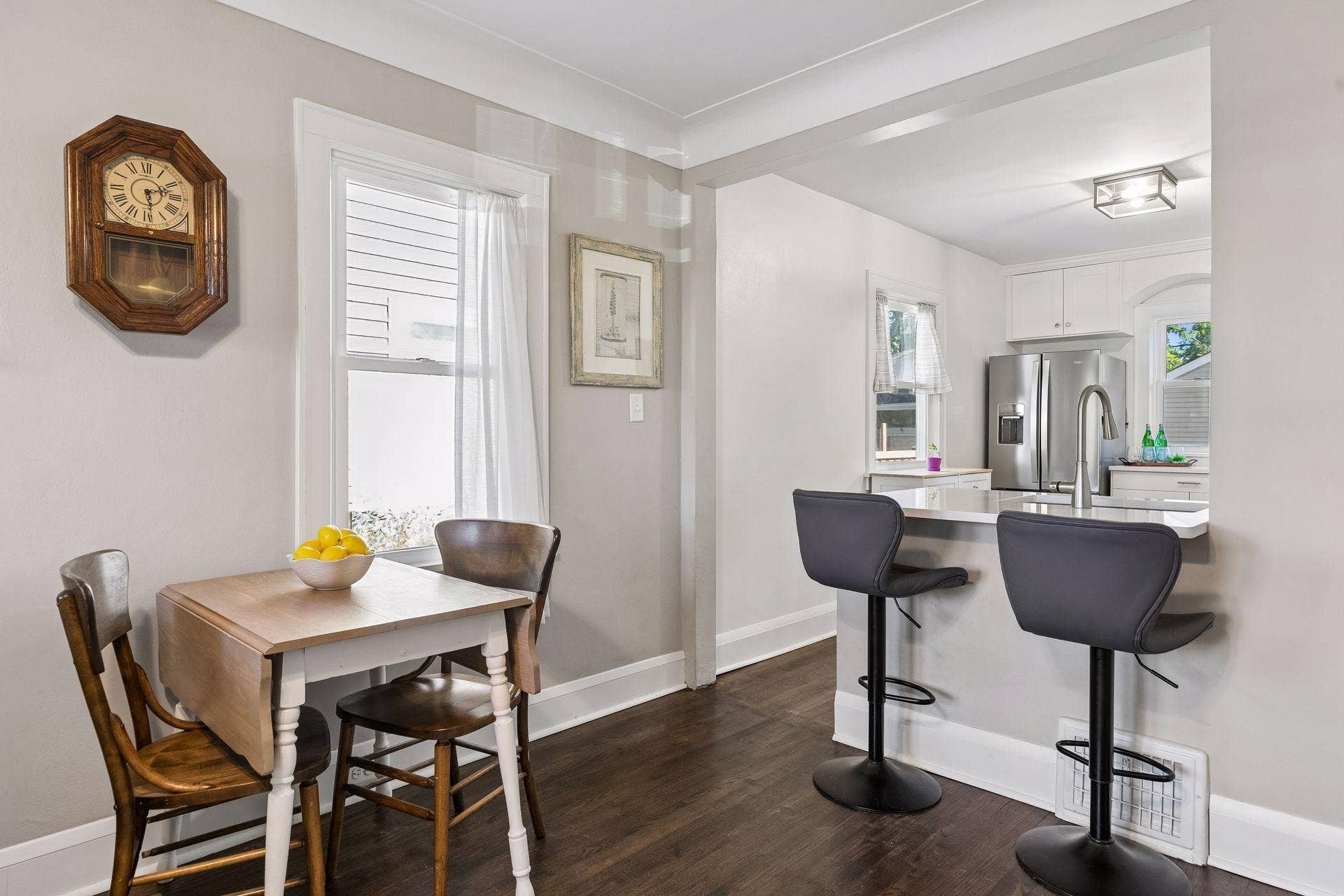 Main-level dining area with hardwood floors and breakfast-bar seating connecting directly to the kitchen.