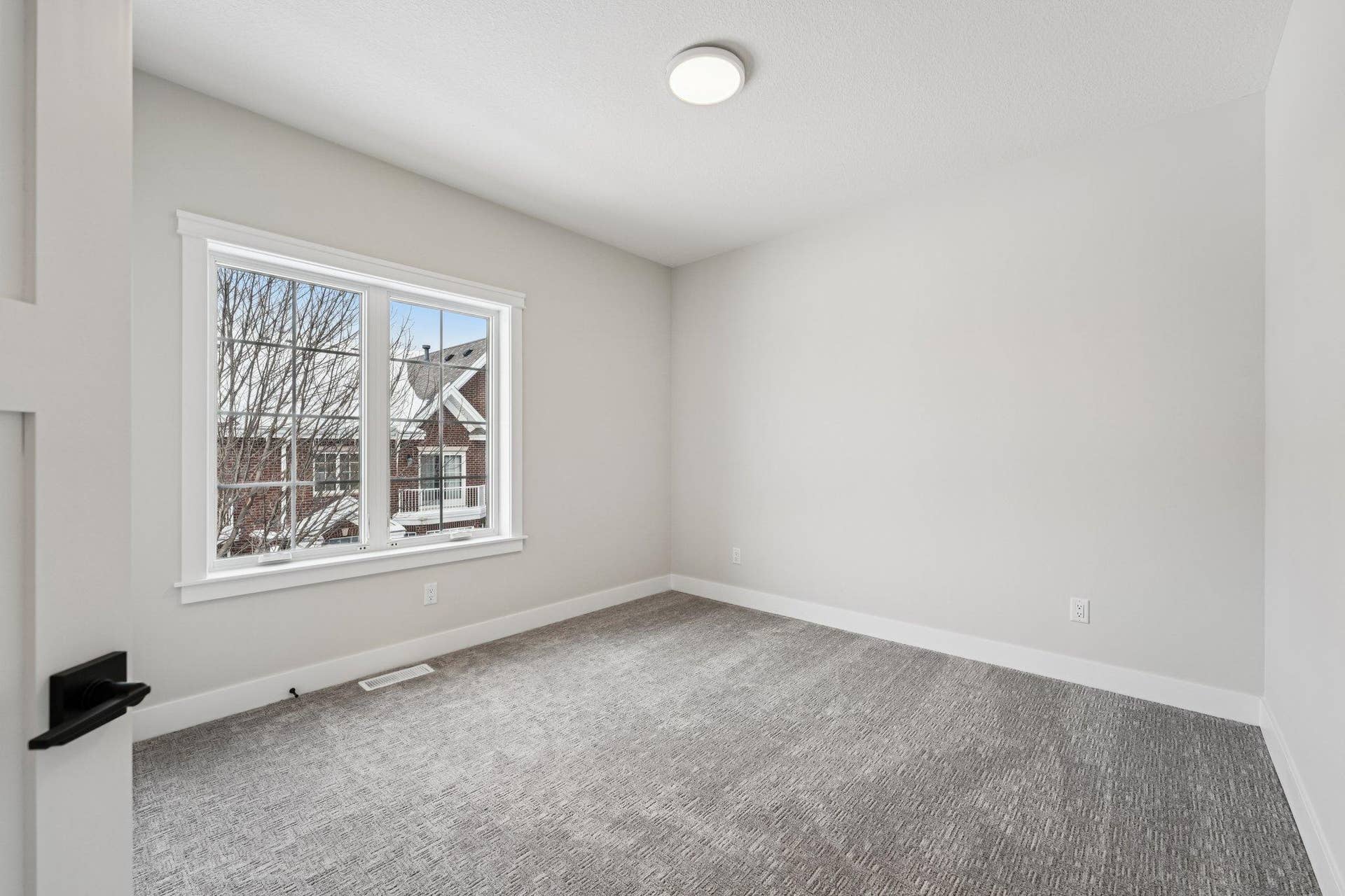 Comfortable bedroom with soft carpeting, oversized window, and ample wall space for furniture placement.