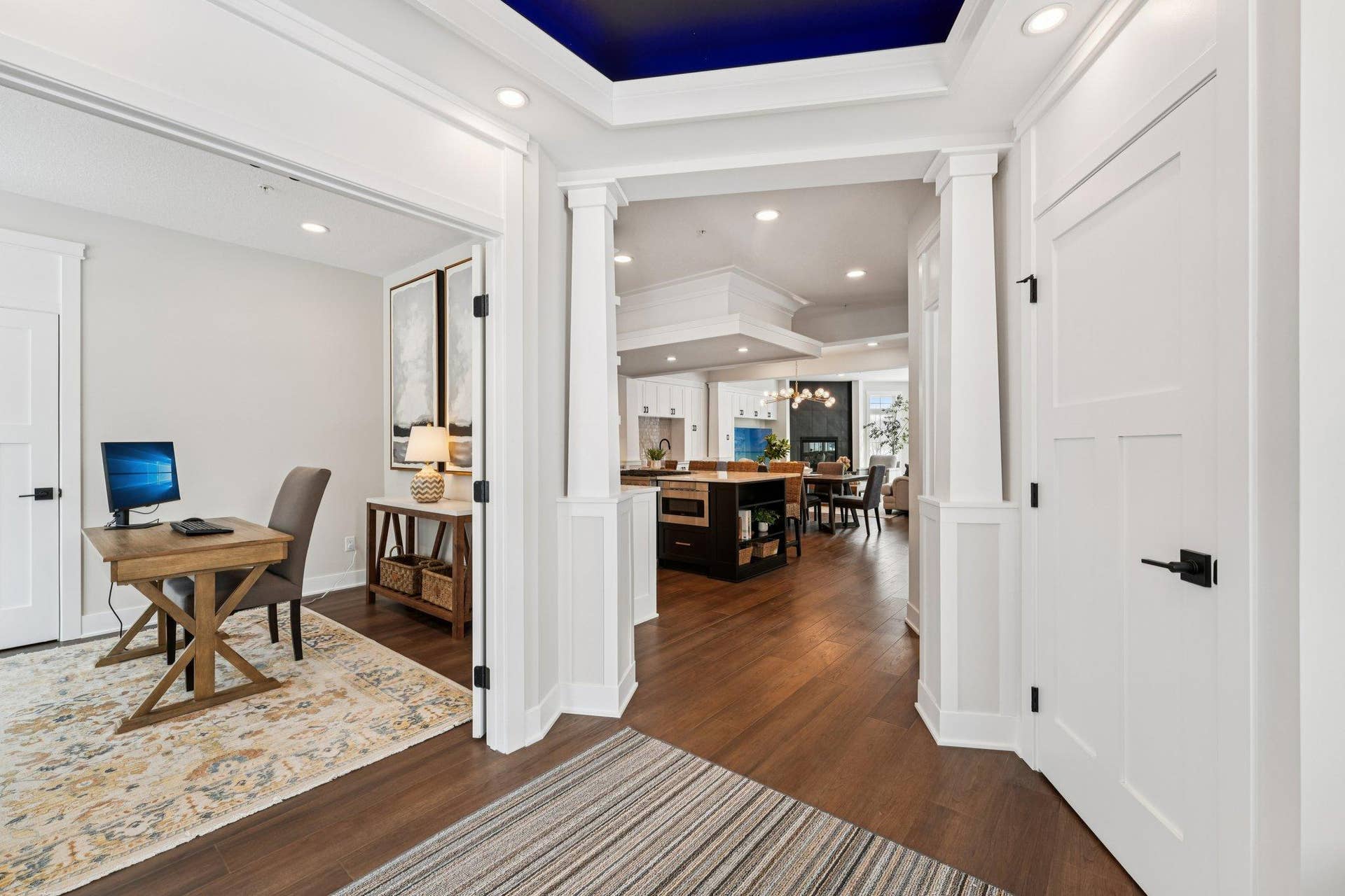 Wide, welcoming foyer showcasing custom millwork, hardwood floors, and a clear sightline into the open main living spaces beyond.