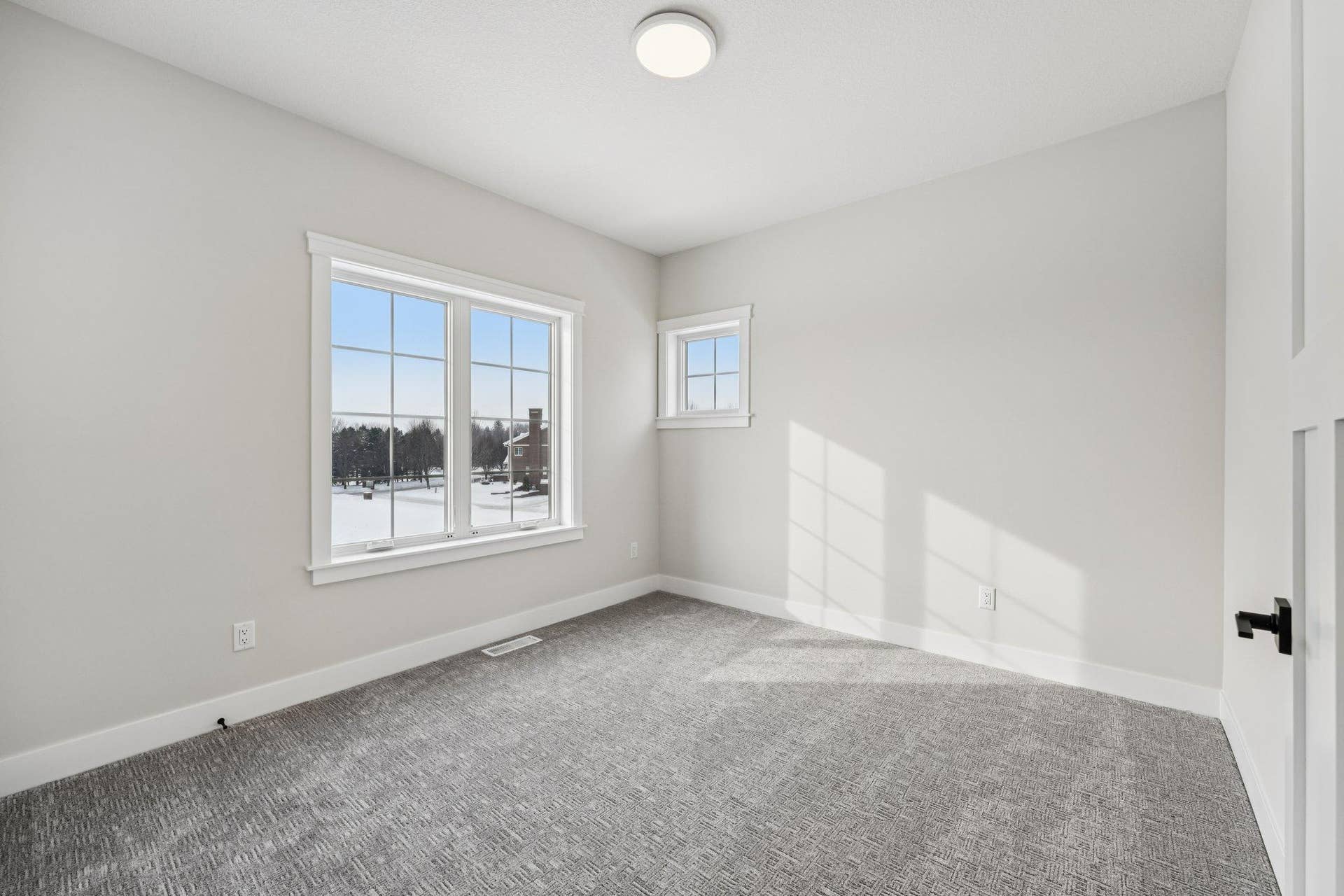 Bright secondary bedroom featuring plush carpet, large windows, and a neutral color palette ready for a variety of uses.