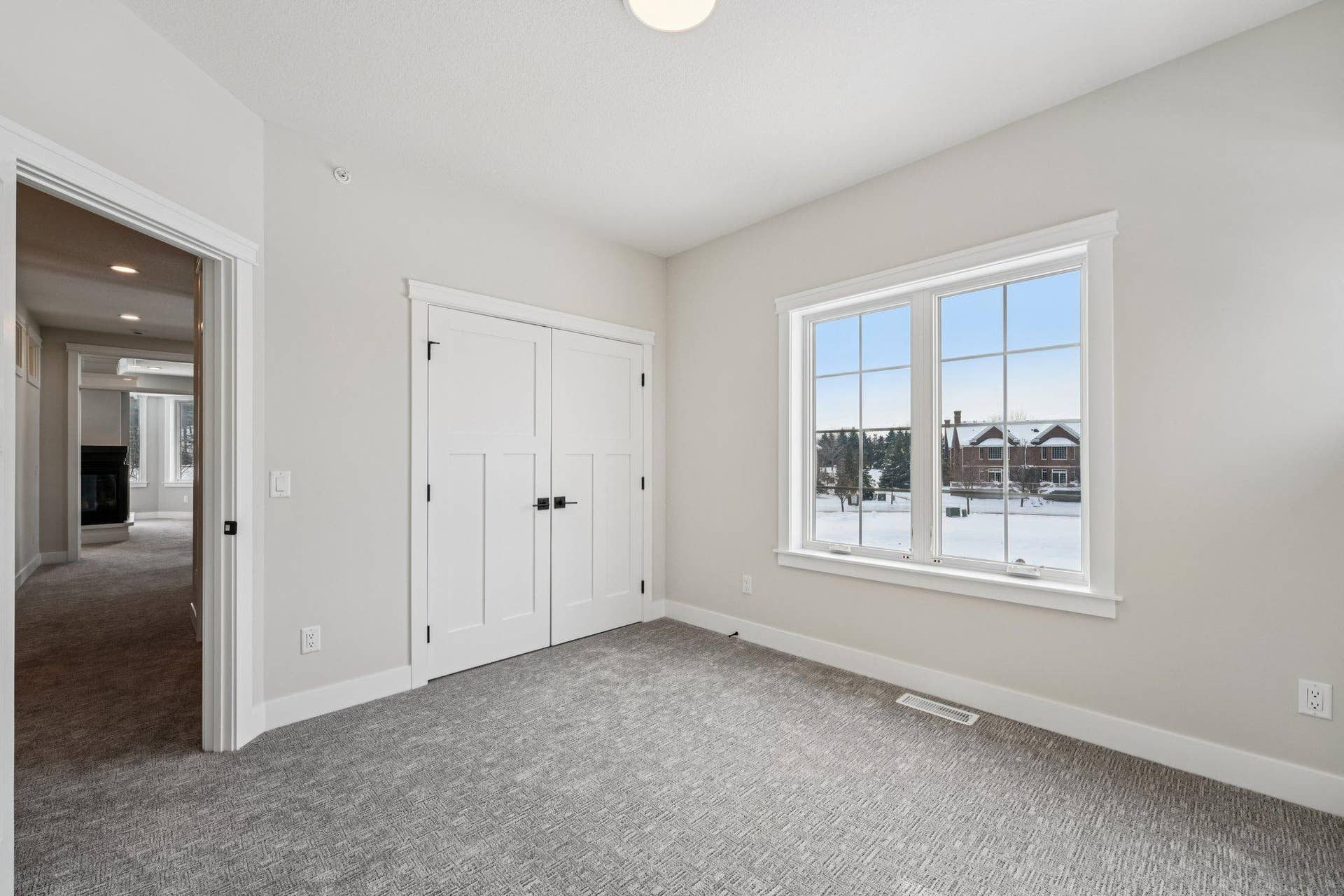 Well-proportioned bedroom showcasing generous natural light, double closet doors, and clean modern finishes.