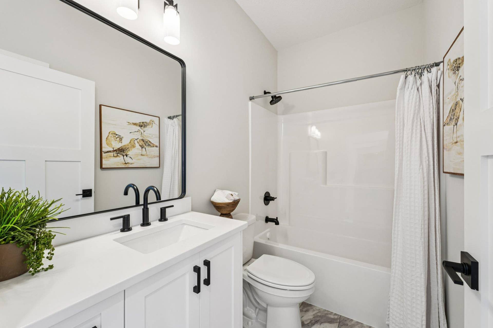 Stylish full bathroom with quartz vanity, modern fixtures, framed mirror, and tub/shower combination.