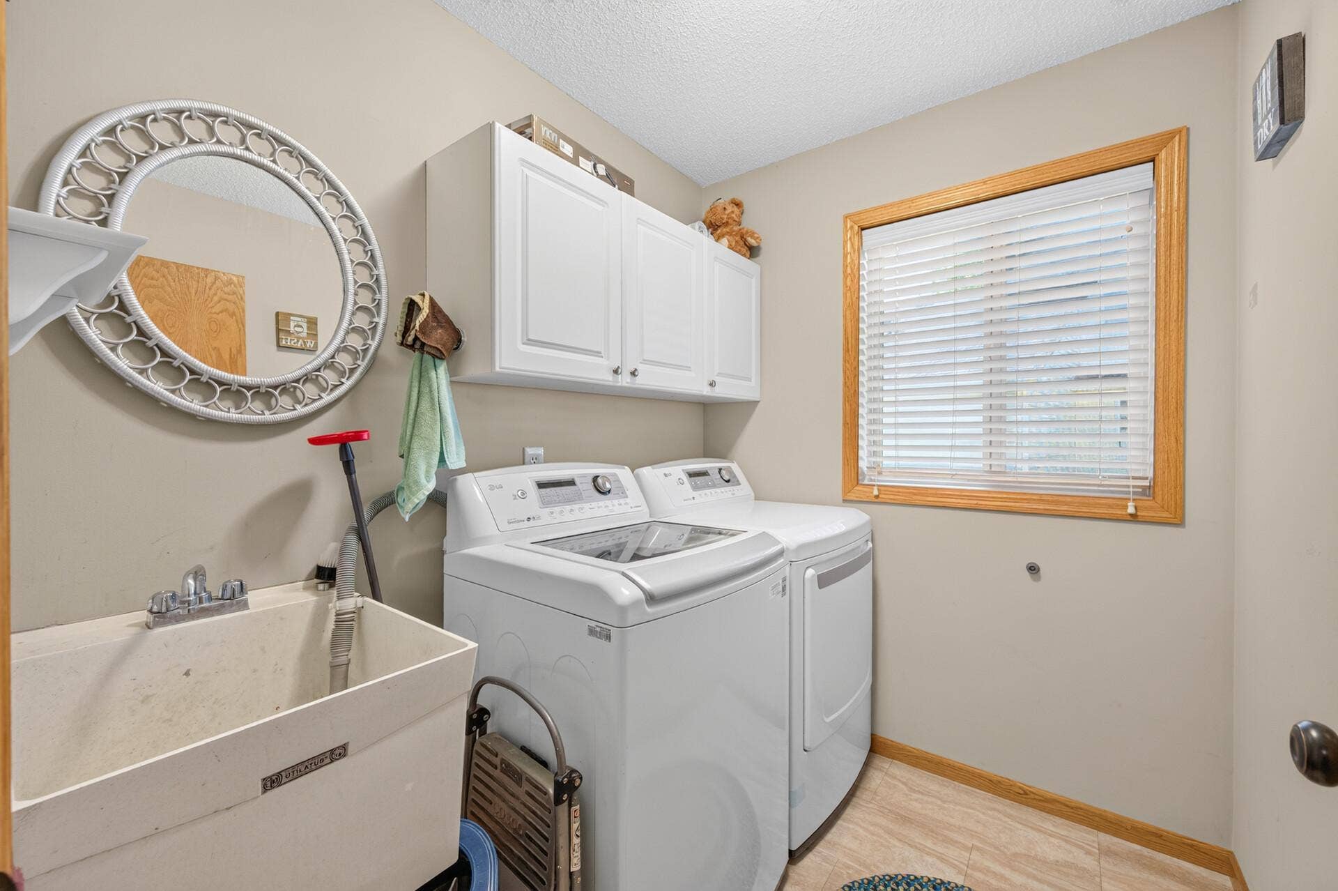3765 Woodside Drive, Monticello, MN 55362 Main-level laundry room with washer, dryer, utility sink, storage cabinets.