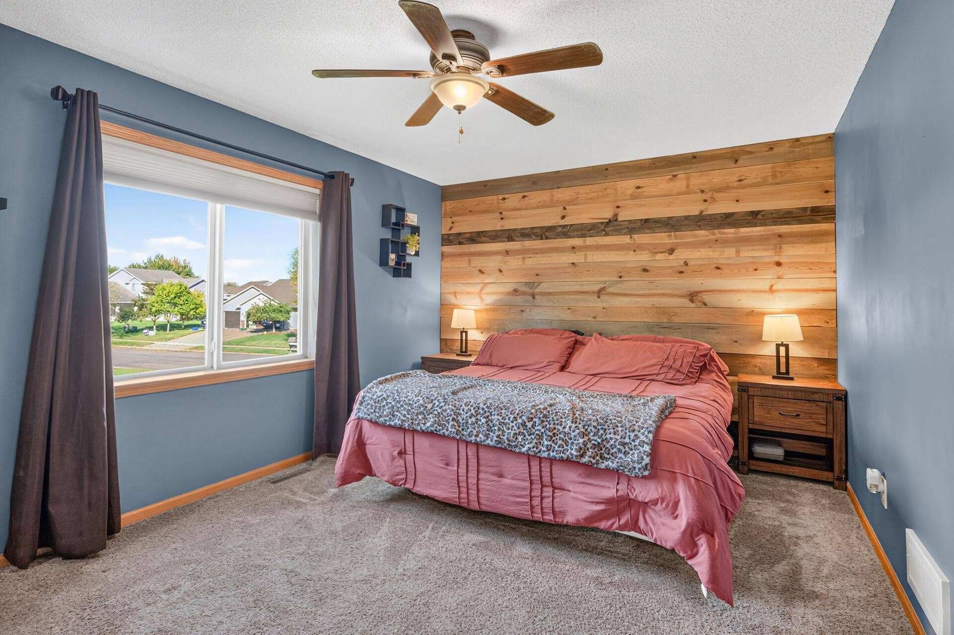 3765 Woodside Drive, Monticello, MN 55362 Spacious upper-level primary suite featuring a beautiful wood accent wall, ceiling fan, and plenty of natural light.