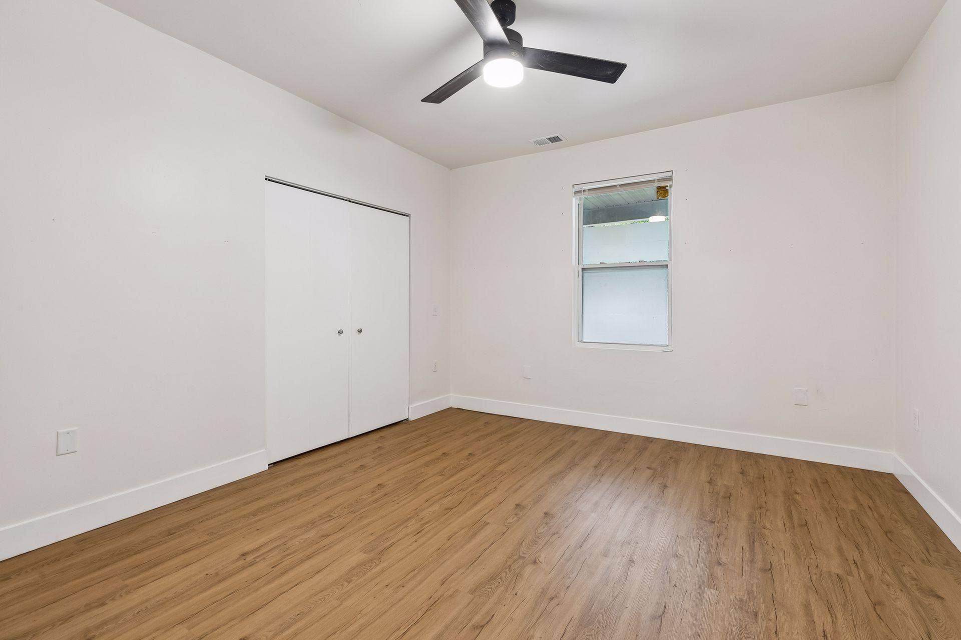2533 Polk Street NE, 2, Minneapolis, MN 55418 Unit 1: A bright and comfortable main-floor bedroom with updated flooring, a ceiling fan with light, and a double closet for extra storage.