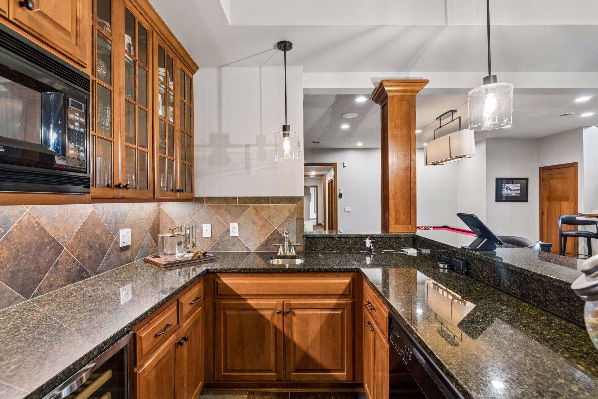 Wet bar with cherry cabinetry, granite counters and seating for three