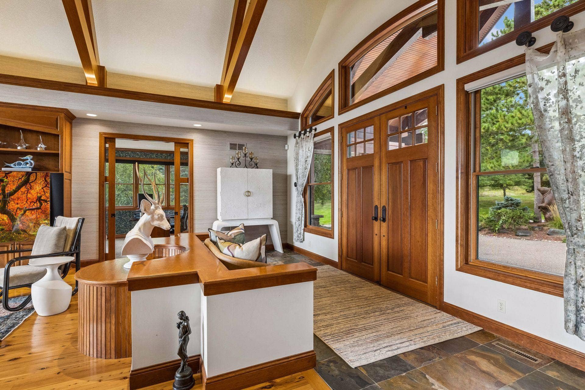 Grand double door entry into great room with soaring vaulted, beamed ceilings