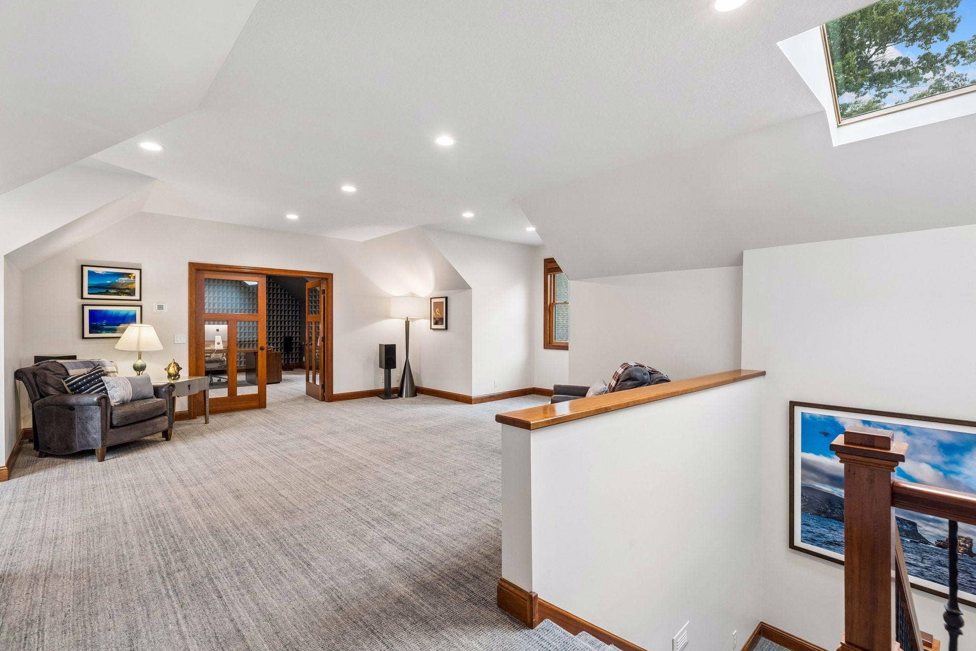 Expansive upper-level bonus room with vaulted dormer ceilings, a skylight, and recessed lighting, offering flexible space for a media room, game room, or lounge, with French doors opening to an adjacent 5th bedroom / office