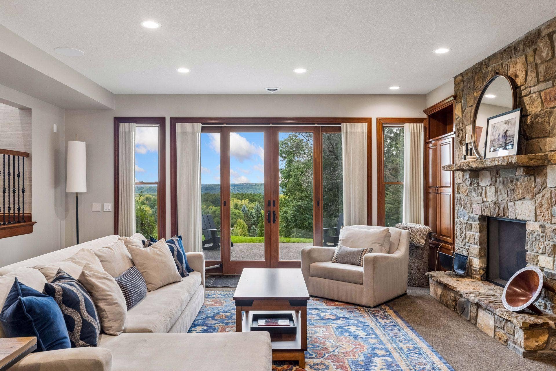 Cozy lower level family room with stone fireplace and French doors opening to St. Croix Valley views