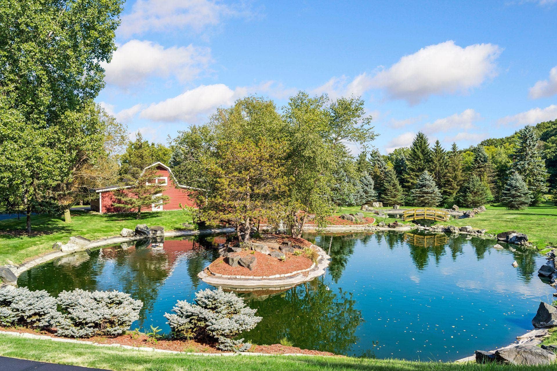 Private landscaped pond with island and footbridge, set beside the historic Civil War era barn
