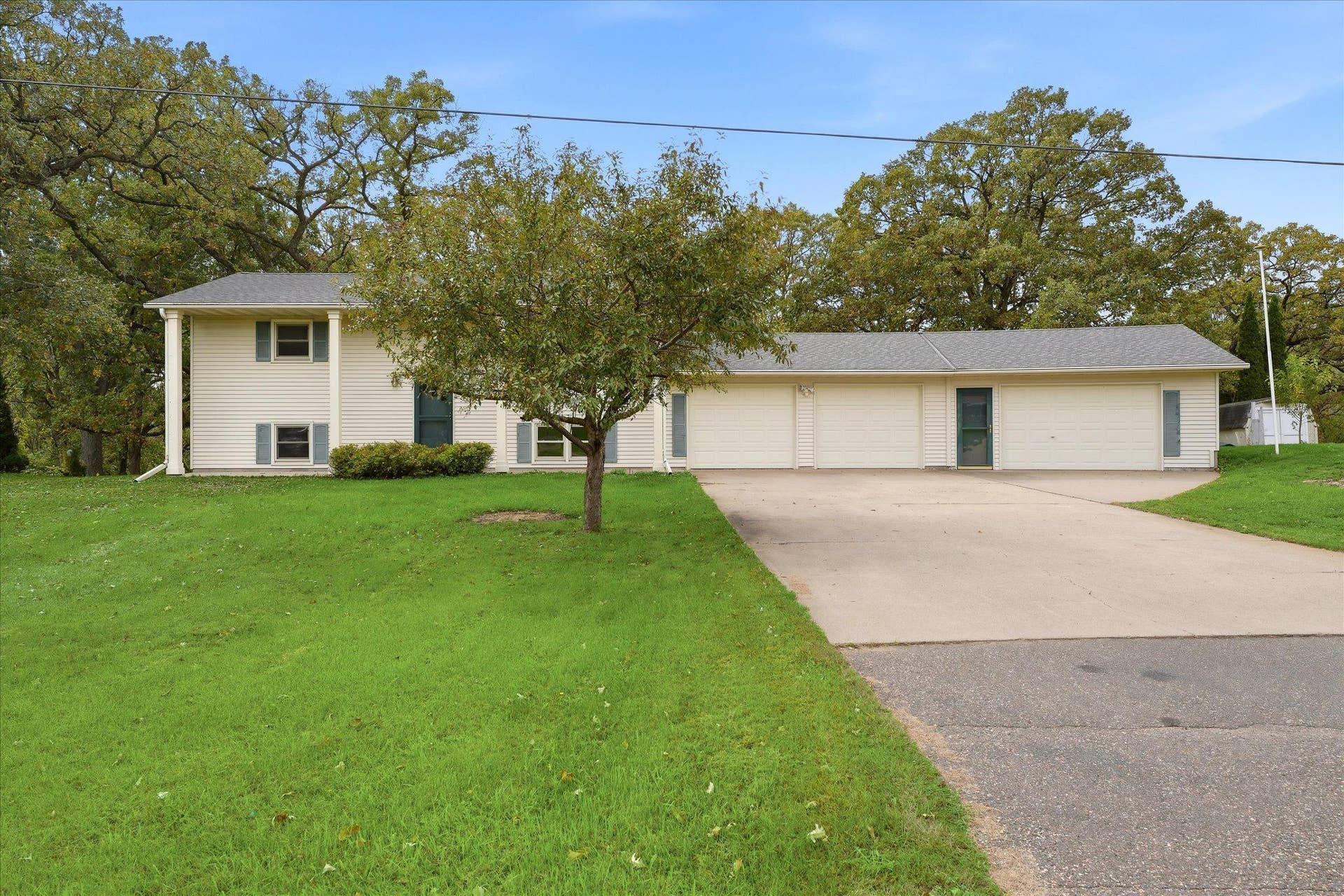 20761 187th Avenue NW, Big Lake, MN 55309 Spacious home featuring an impressive attached three-car garage (3rd stall is heated), expansive concrete driveway, and mature trees surrounding the property.