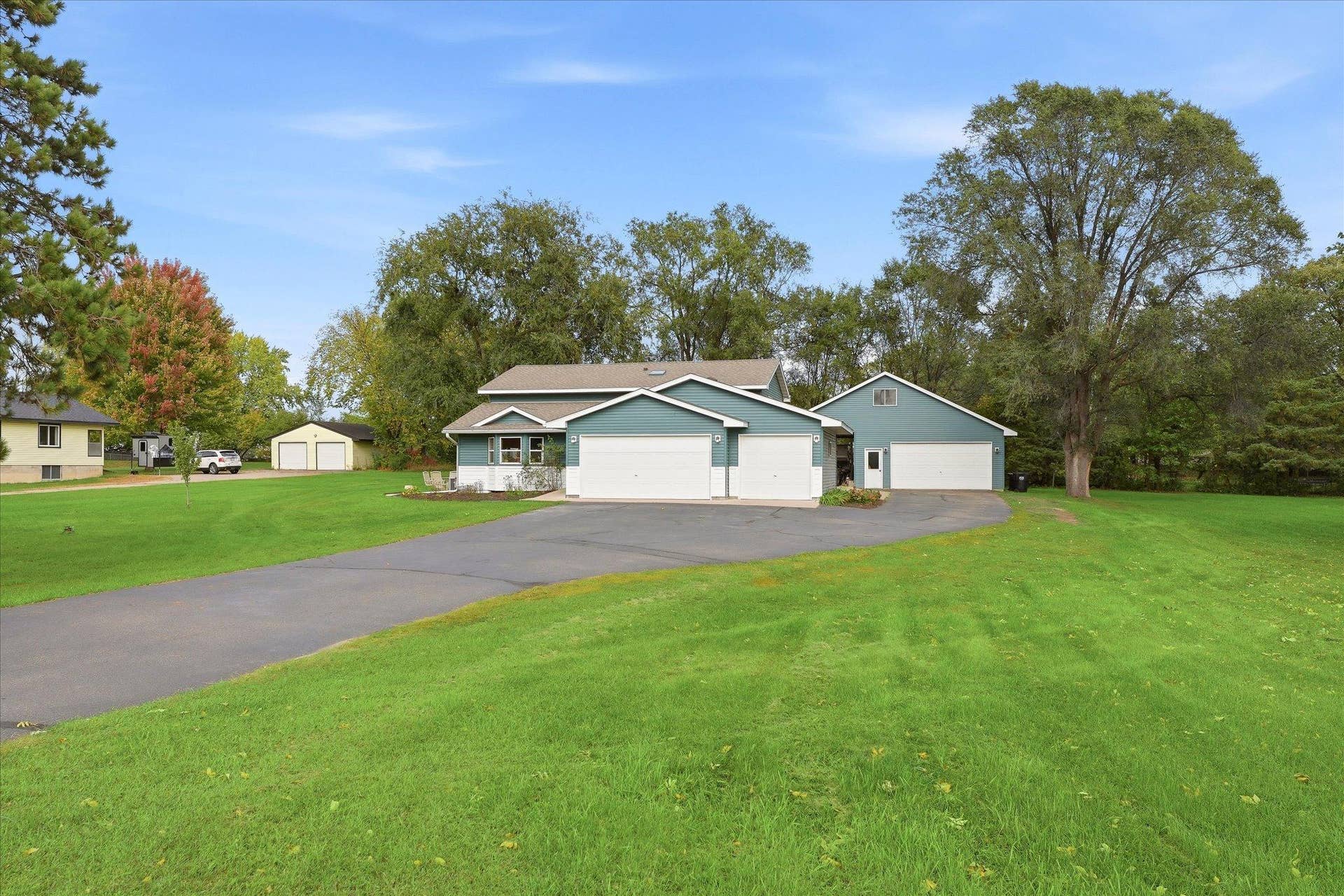 20720 187th Avenue NW, Big Lake, MN 55309 Welcoming exterior situated on a spacious lot with mature trees, an expansive driveway, attached three-car garage, and impressive detached garage for additional parking and storage.