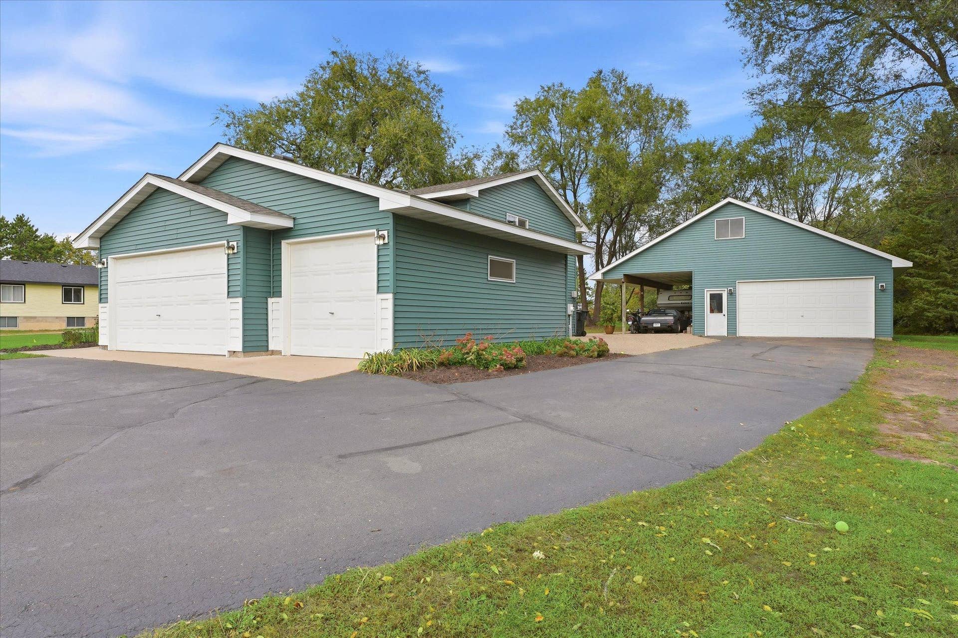 20720 187th Avenue NW, Big Lake, MN 55309 Exceptional garage space includes an attached three-car garage plus a large detached garage with an additional covered area, ideal for vehicles, recreational equipment, hobbies, or extra storage.