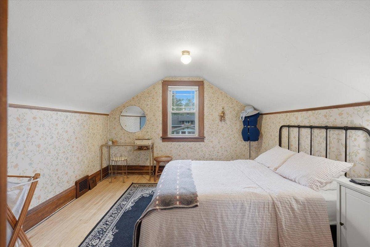 Tucked away, the upper-level bedroom has a cozy character all of its own with hardwood floors and vintage-inspired floral detail.