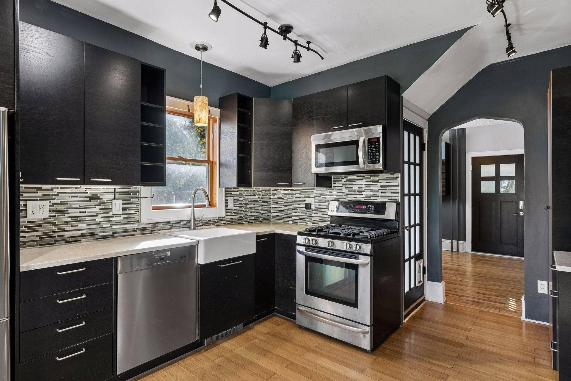3112 E 33rd Street, 44, Minneapolis, MN 55406 Bamboo flooring and track lighting complement the farmhouse sink, tile backsplash, and generous recycled resin countertop space. A window with a modern pendant light adds warmth and natural light.