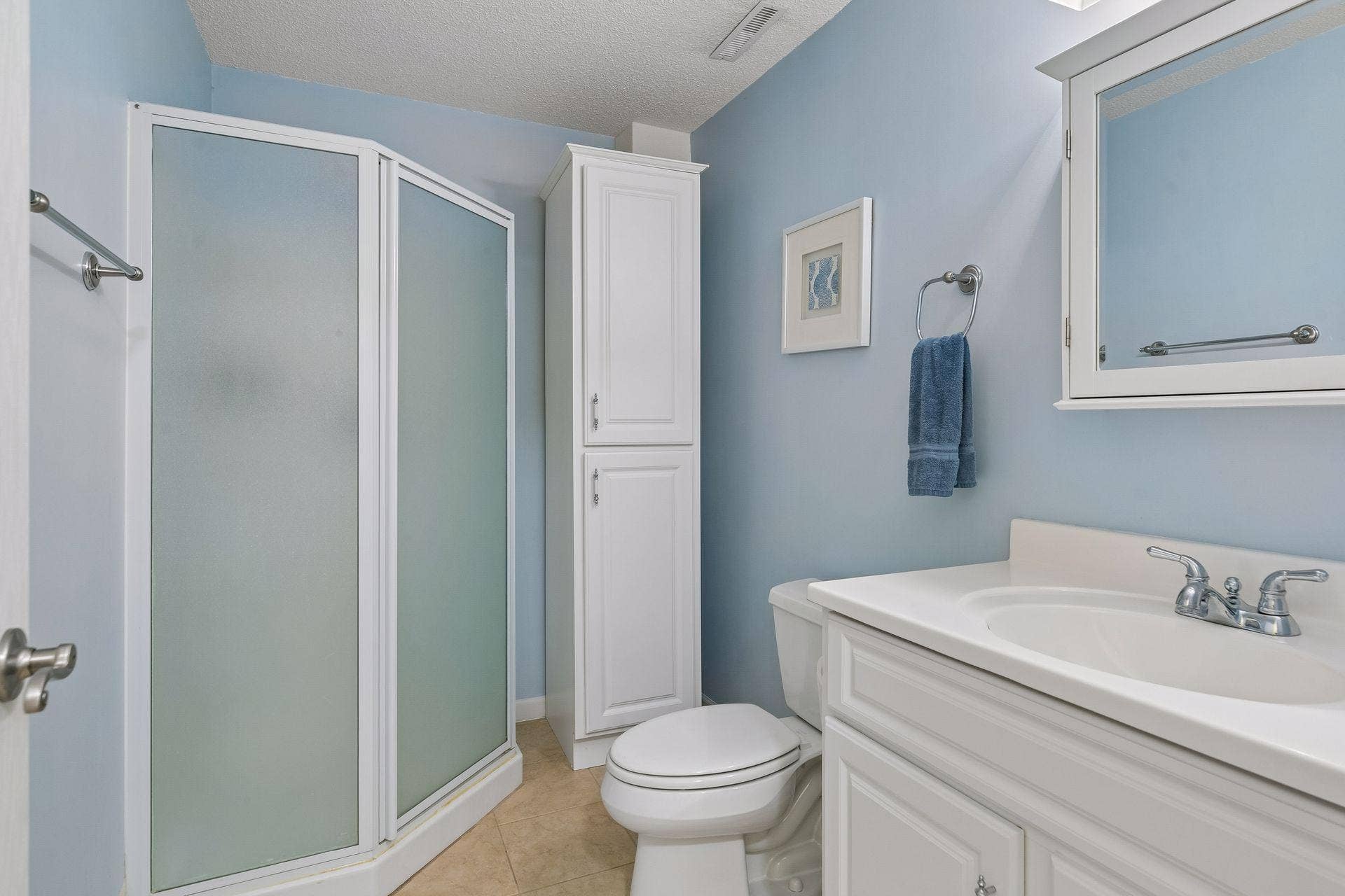 957 Lake Ridge Bay, Woodbury, MN 55129 The lower level 3/4 bath provides a clean, functional space featuring tile flooring, vanity with mirrored medicine cabinet, wall lighting, and shower stall.
