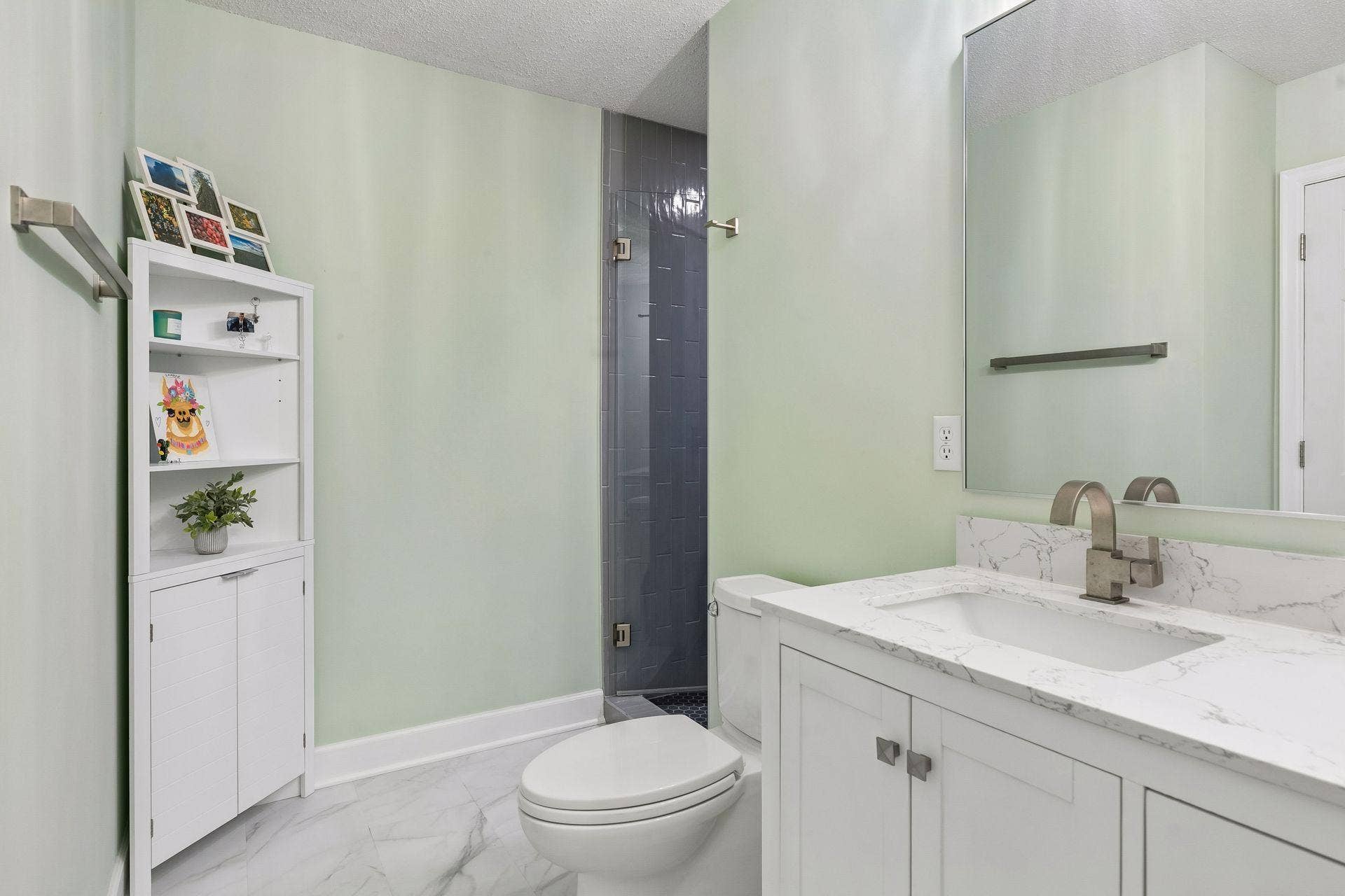 957 Lake Ridge Bay, Woodbury, MN 55129 Start and end your day in the beautifully updated primary 3/4 bath, featuring a spacious double vanity, LVP flooring, wall lighting, and a gorgeous tiled shower with a custom glass door.