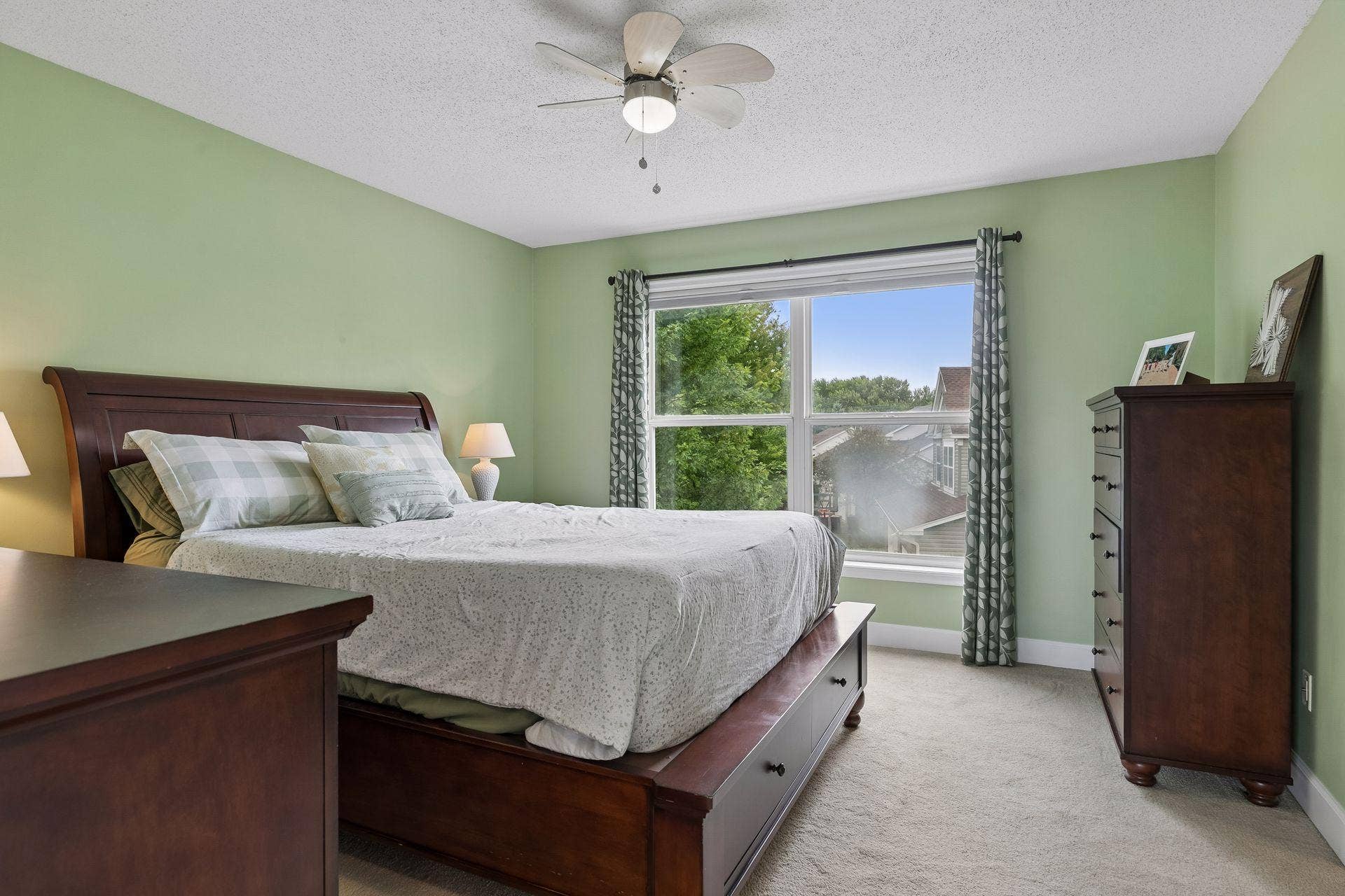 957 Lake Ridge Bay, Woodbury, MN 55129 The spacious primary bedroom is filled with natural light from a large double window and offers soft carpet flooring, ample space and a ceiling fan with light.