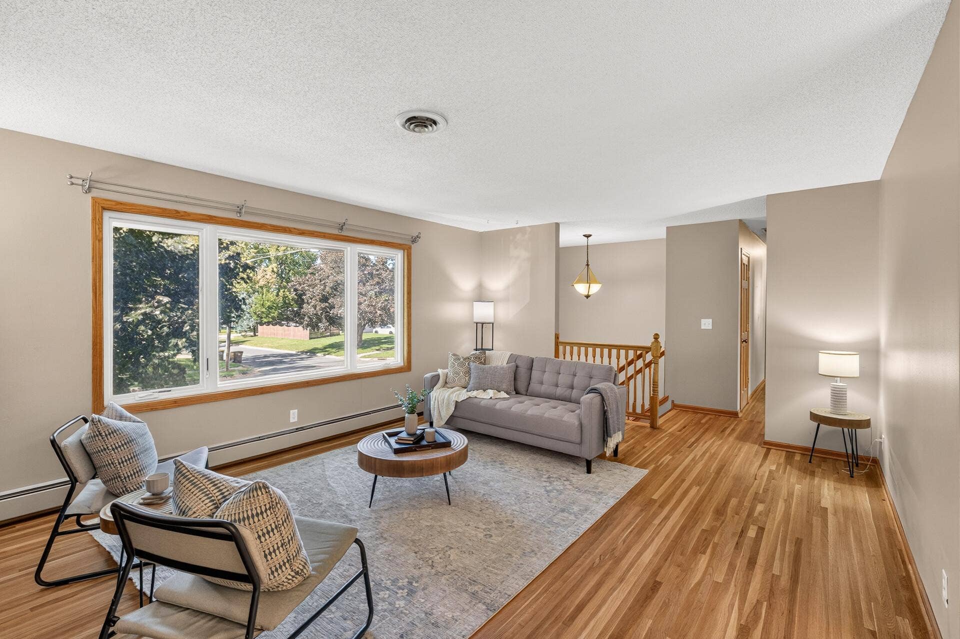 The spacious living room, with freshly finished hardwood floors, flows seamlessly into the dining area, creating the perfect space for entertaining family and friends.