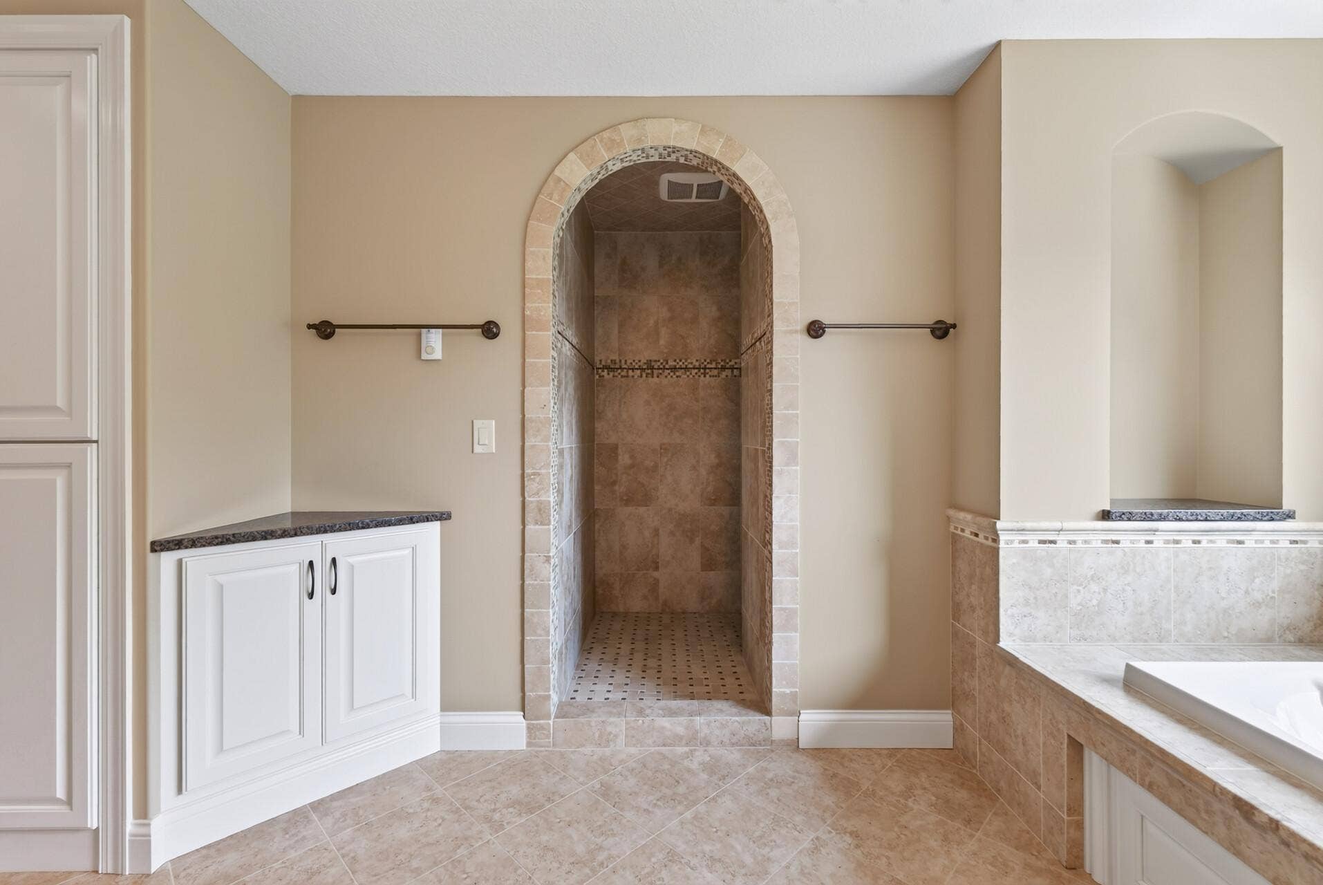 A graceful curved entry leads into the expansive tiled walk-in shower, adding architectural interest and a custom, spa-inspired feel to the primary bath.