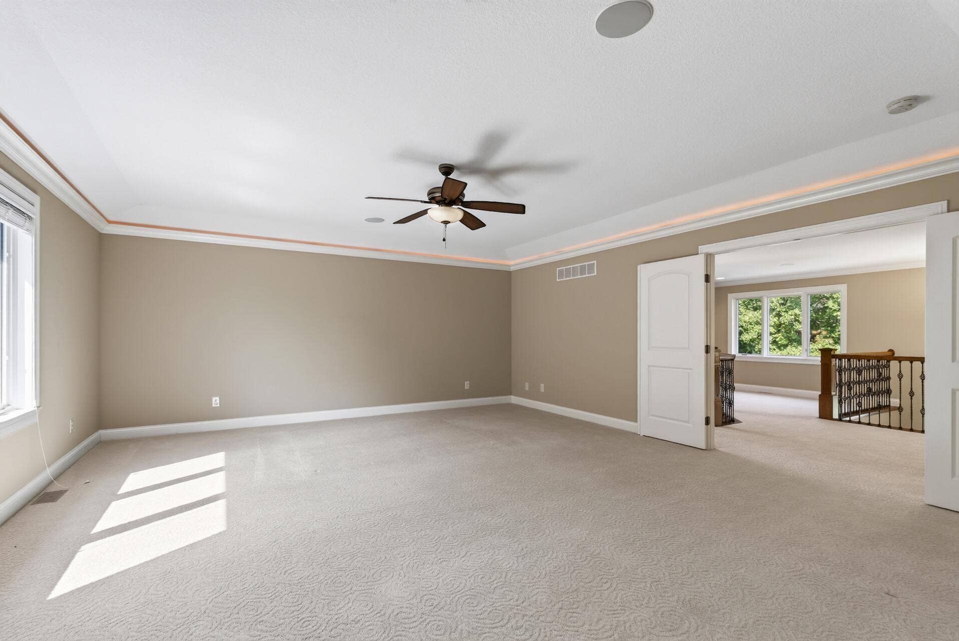 Cove lighting beautifully accentuates the primary suites tray-vaulted ceiling, while a ceiling fan adds everyday comfort to this spacious and serene retreat.