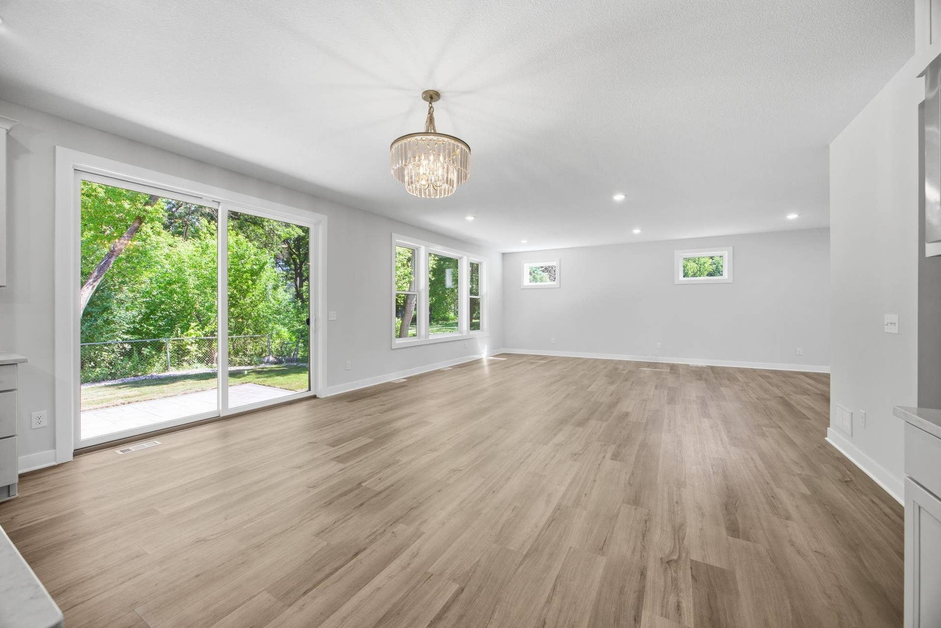 2399 Laurie Court W, Roseville, MN 55113 This unfurnished view highlights the open-concept living room and informal dining area, featuring abundant natural light, oversized windows, and a sliding glass door leading to the spacious outdoor patio.